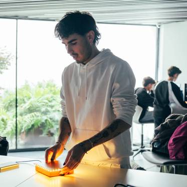 Un joven está manipulando un objeto luminoso mientras un hombre observa al fondo.