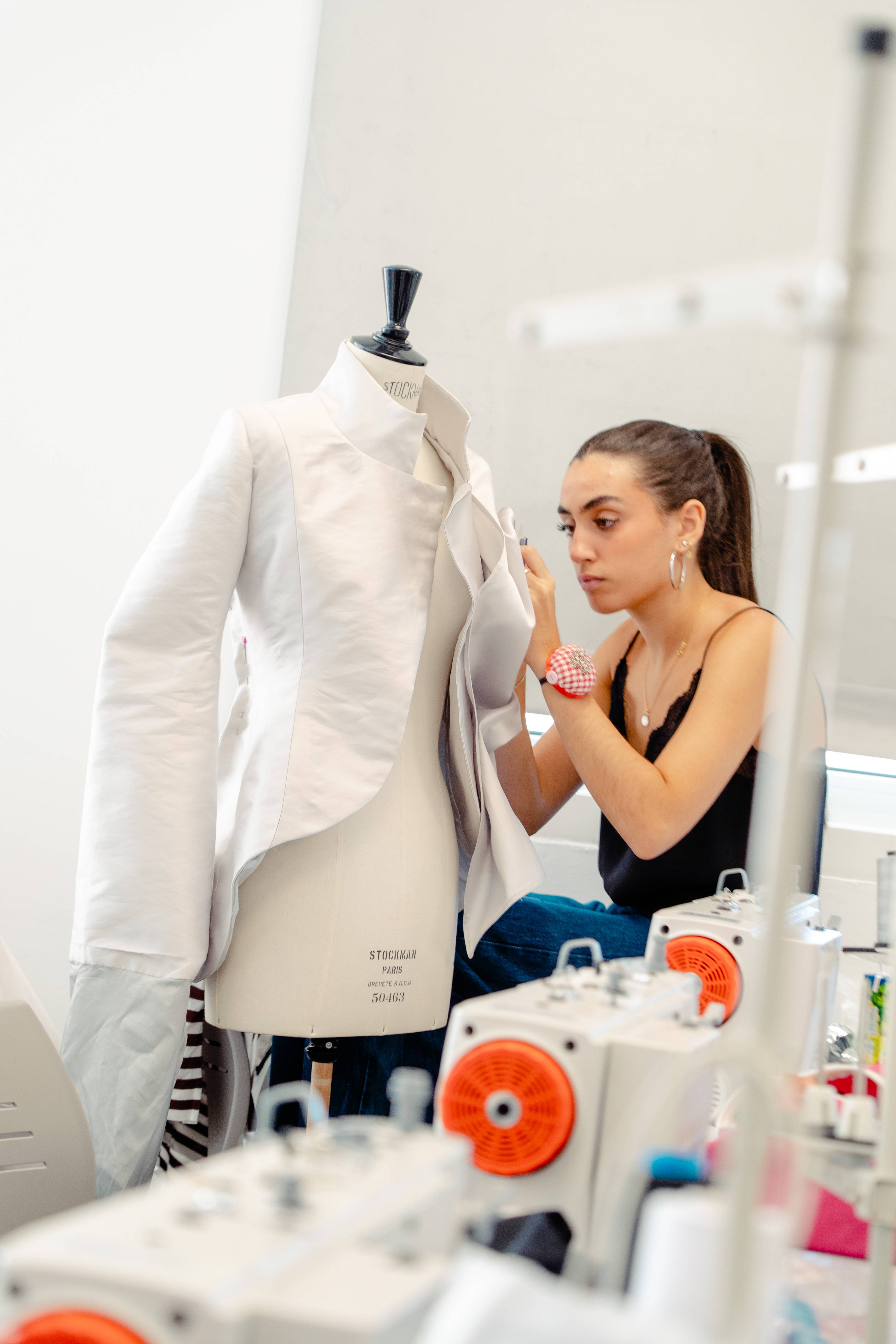 Una diseñadora de moda trabaja en una prenda utilizando una máquina de coser en su estudio.