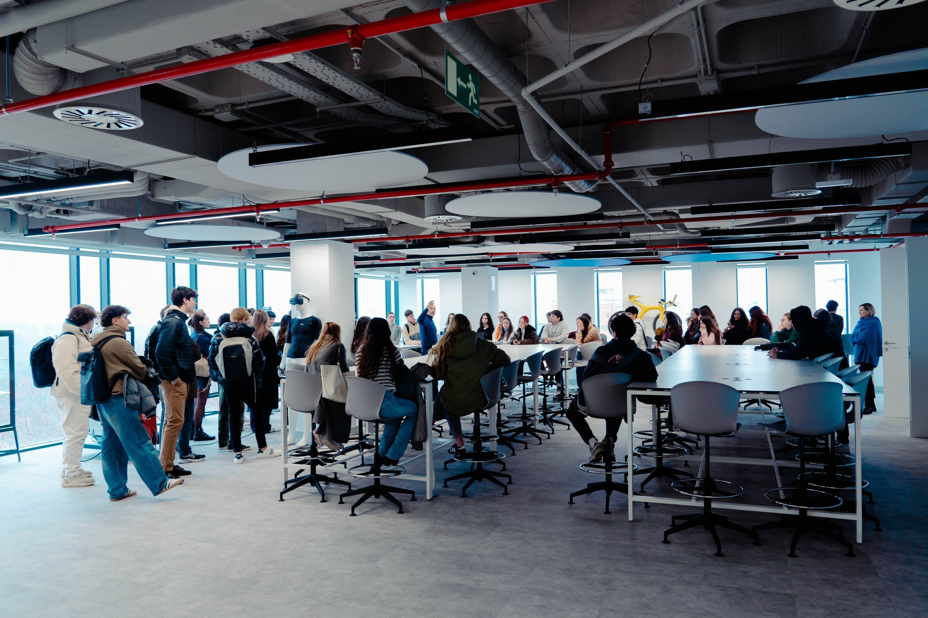 Una gran sala de reuniones con grupos de personas conversando alrededor de mesas altas.