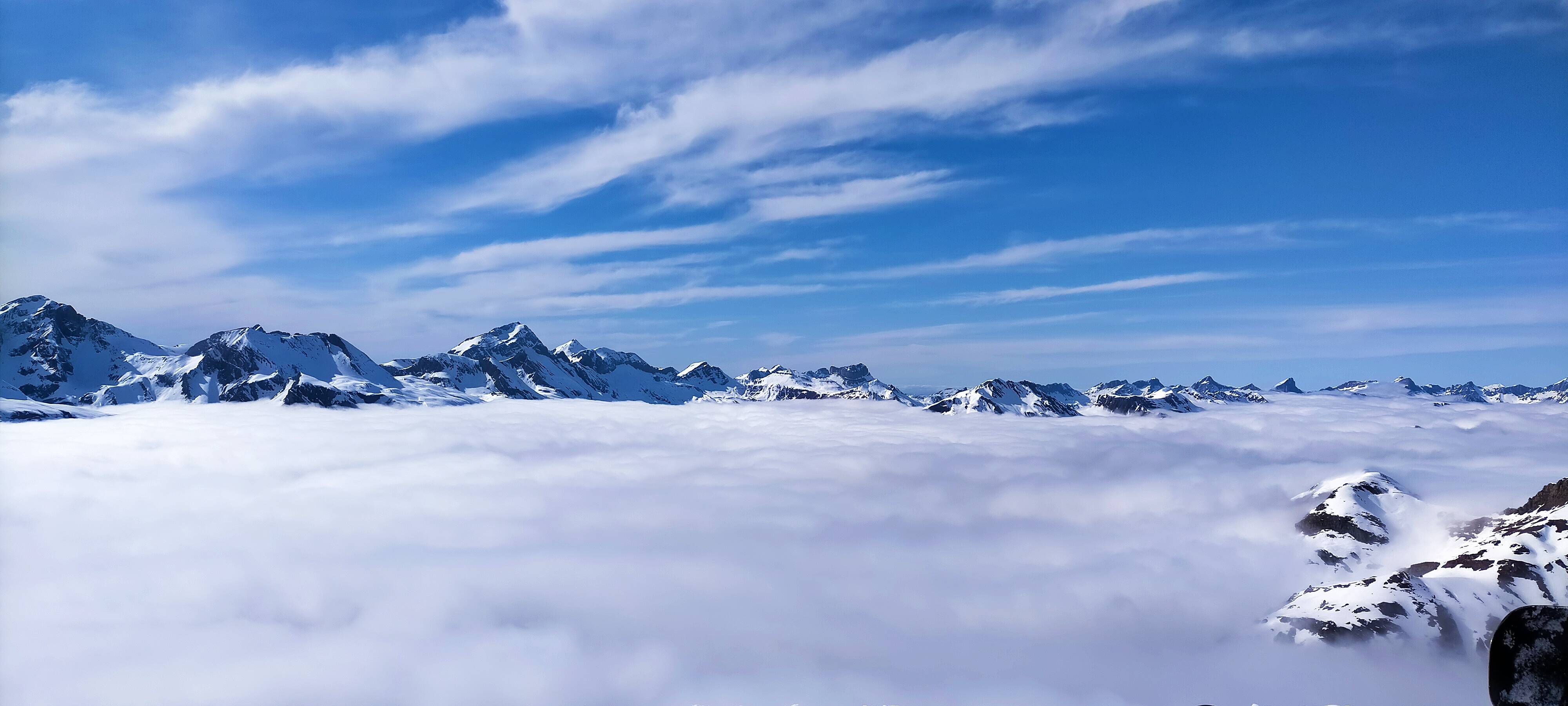 Una vista panorámica de montañas cubiertas de nieve sobre un mar de nubes.