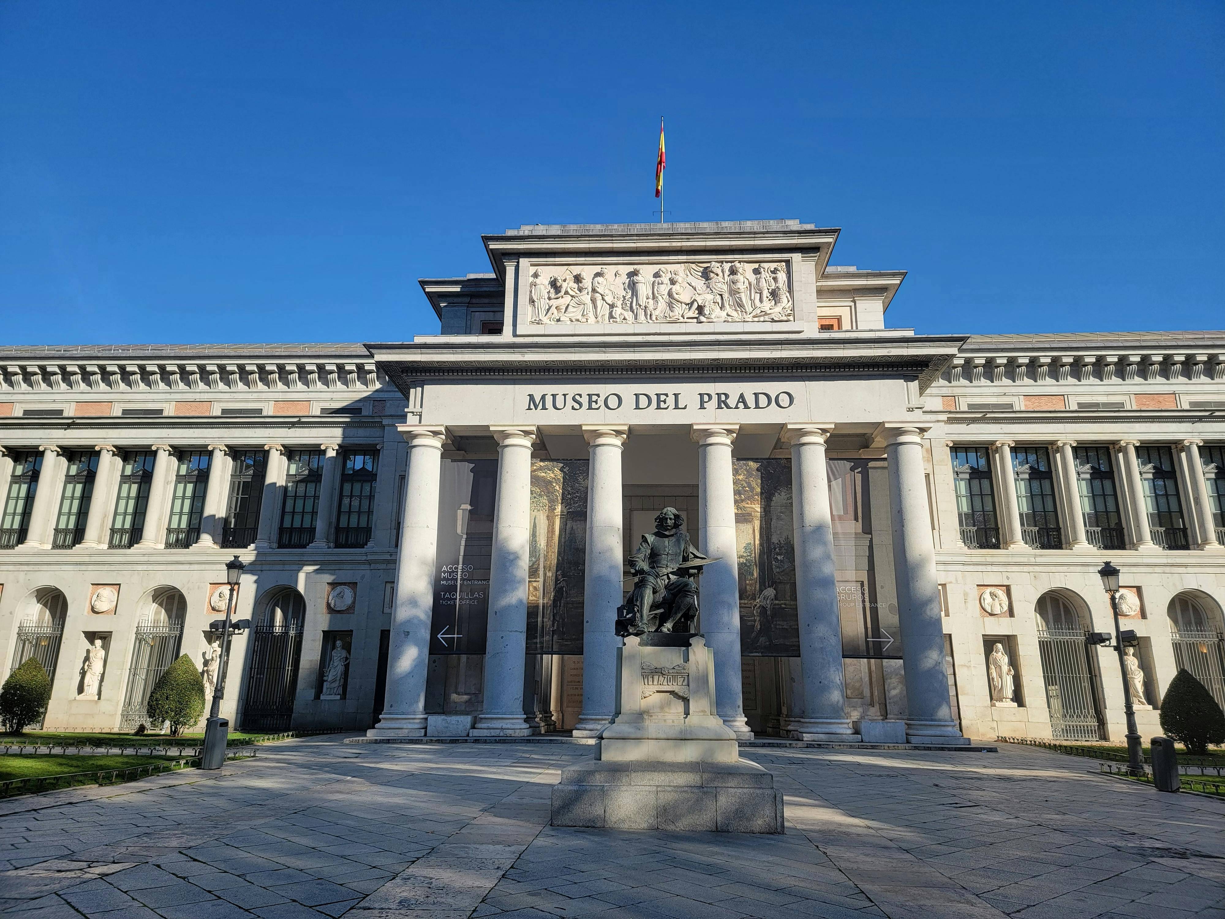 La imagen muestra la fachada del Museo del Prado en Madrid, iluminada por la luz del día.
