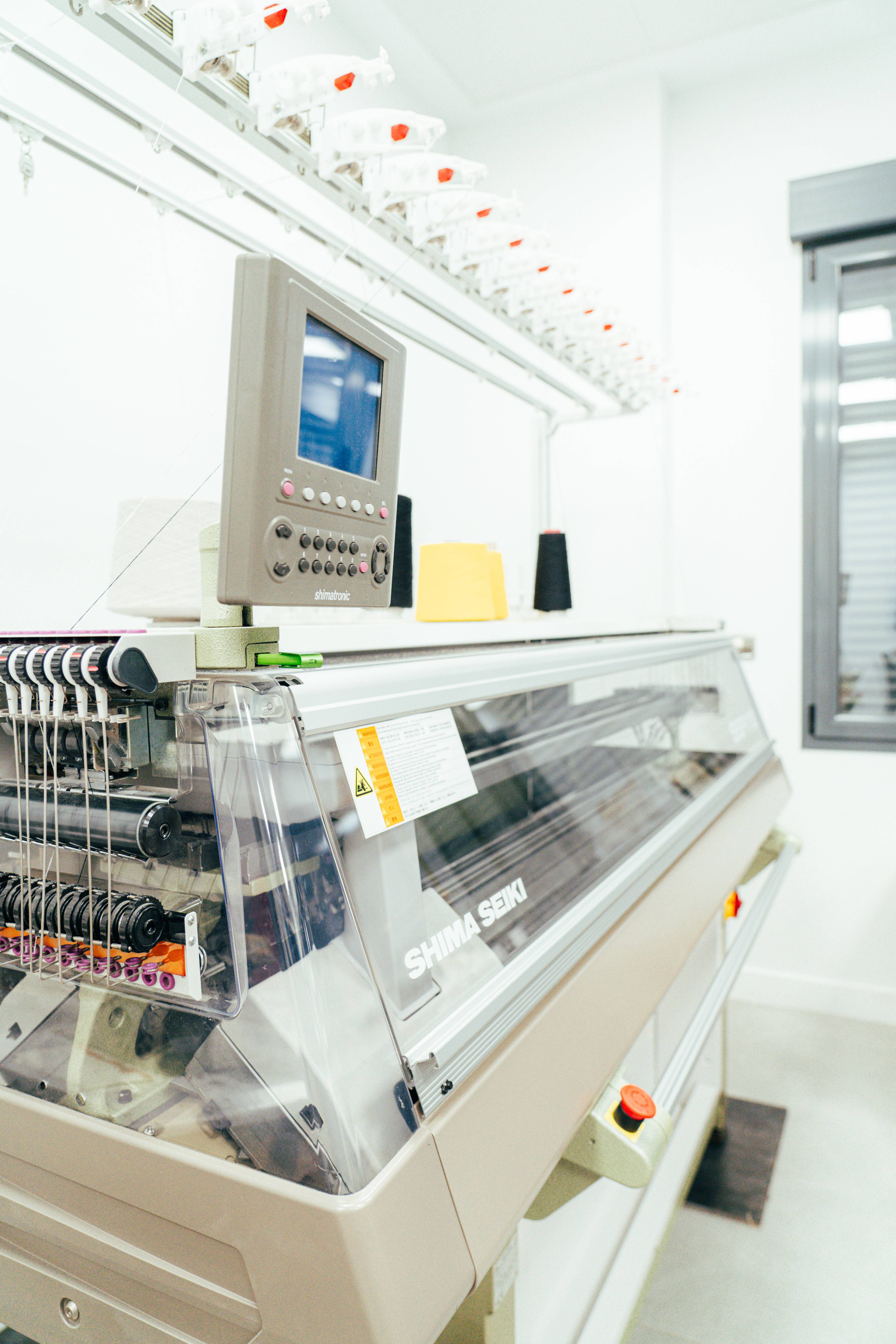 La imagen muestra una máquina de bordar moderna en un entorno de trabajo industrial.