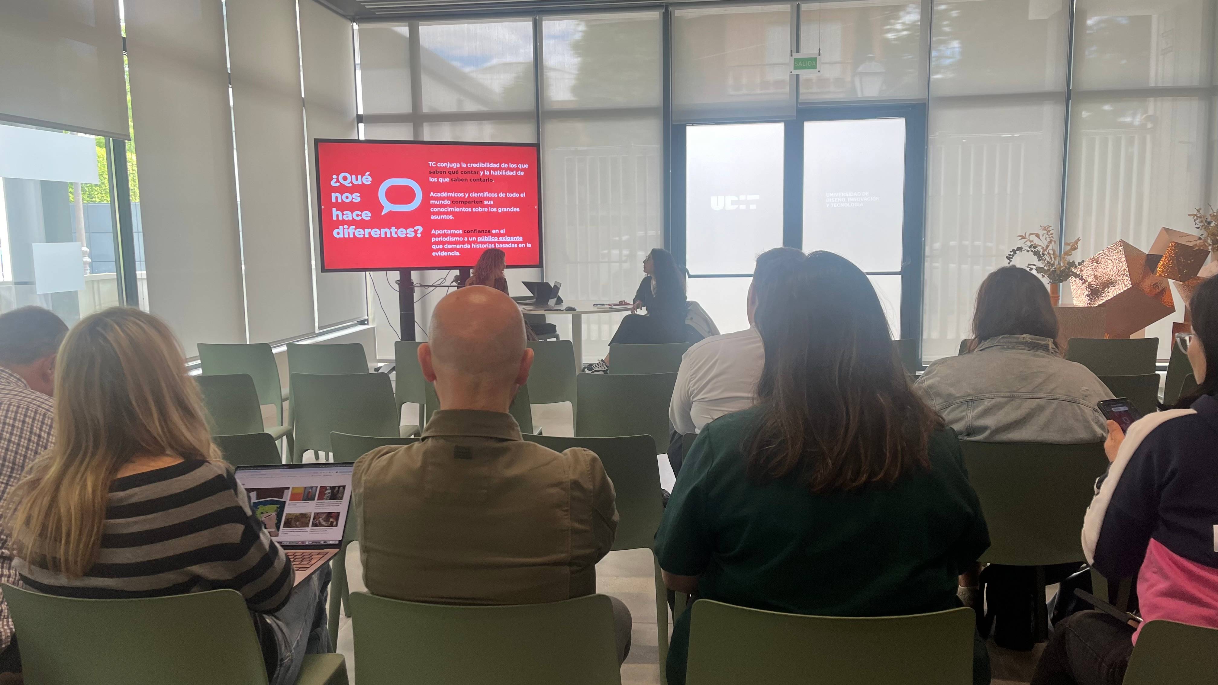 Un grupo de personas asiste a una charla en un salón con una presentación en pantalla.
