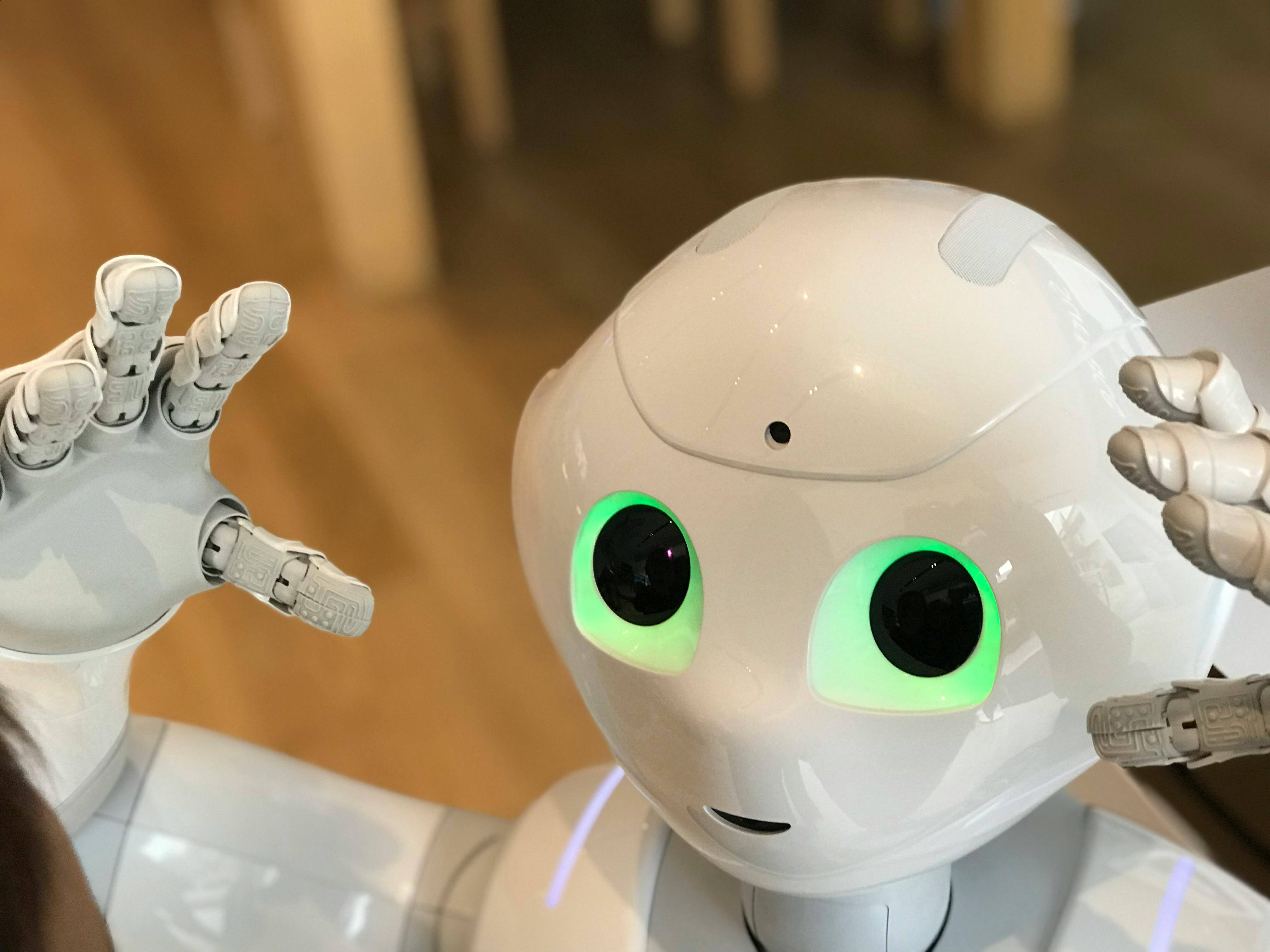 Un robot con ojos verdes y una expresión amigable levanta sus manos.