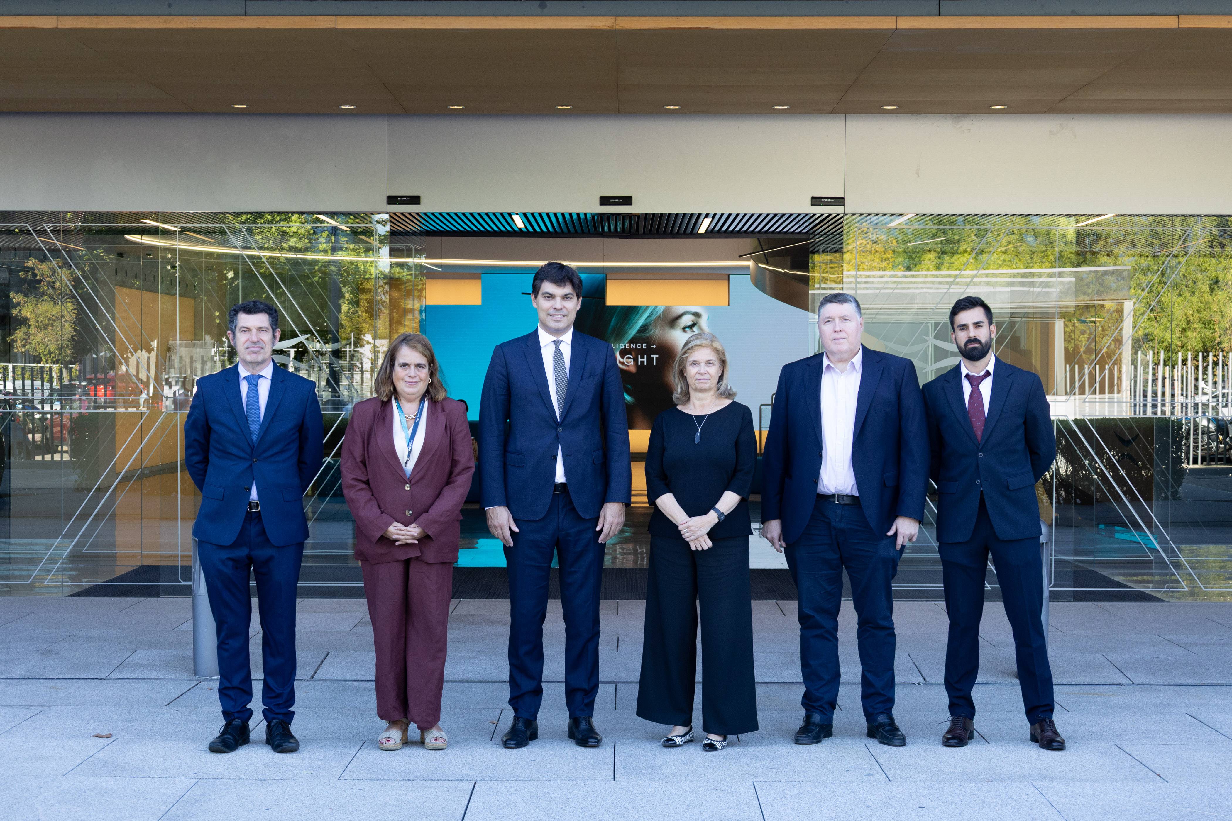 Un grupo de seis personas posan frente a un edificio moderno con un fondo colorido.