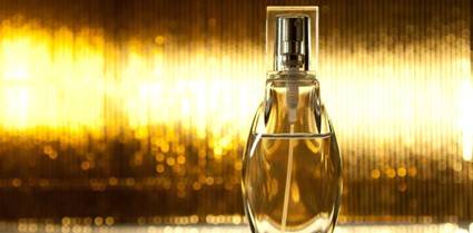 Frasco de perfume elegantemente exhibido frente a un fondo dorado brillante.