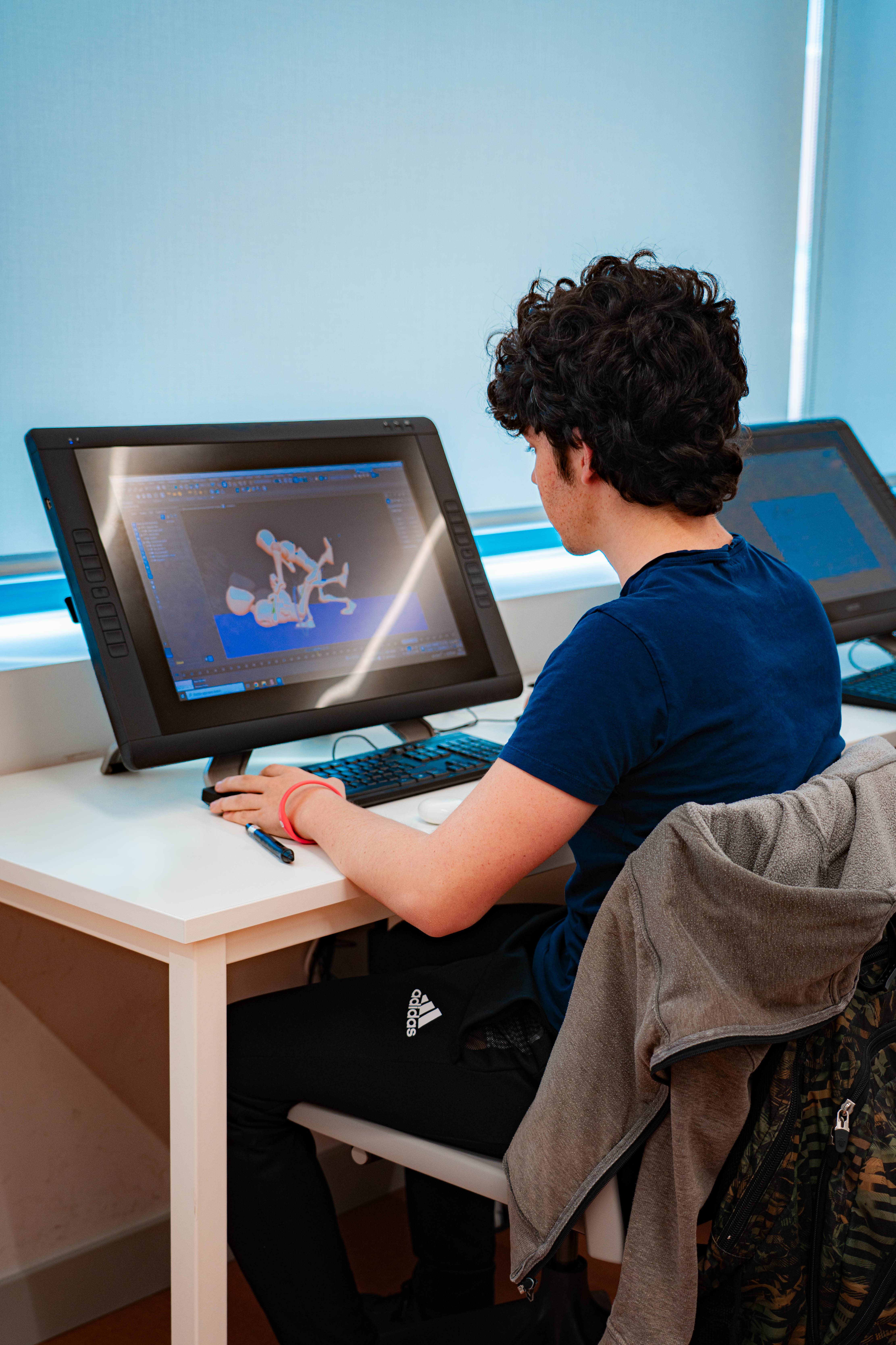 Un joven trabaja en una computadora gráfica en un entorno iluminado.