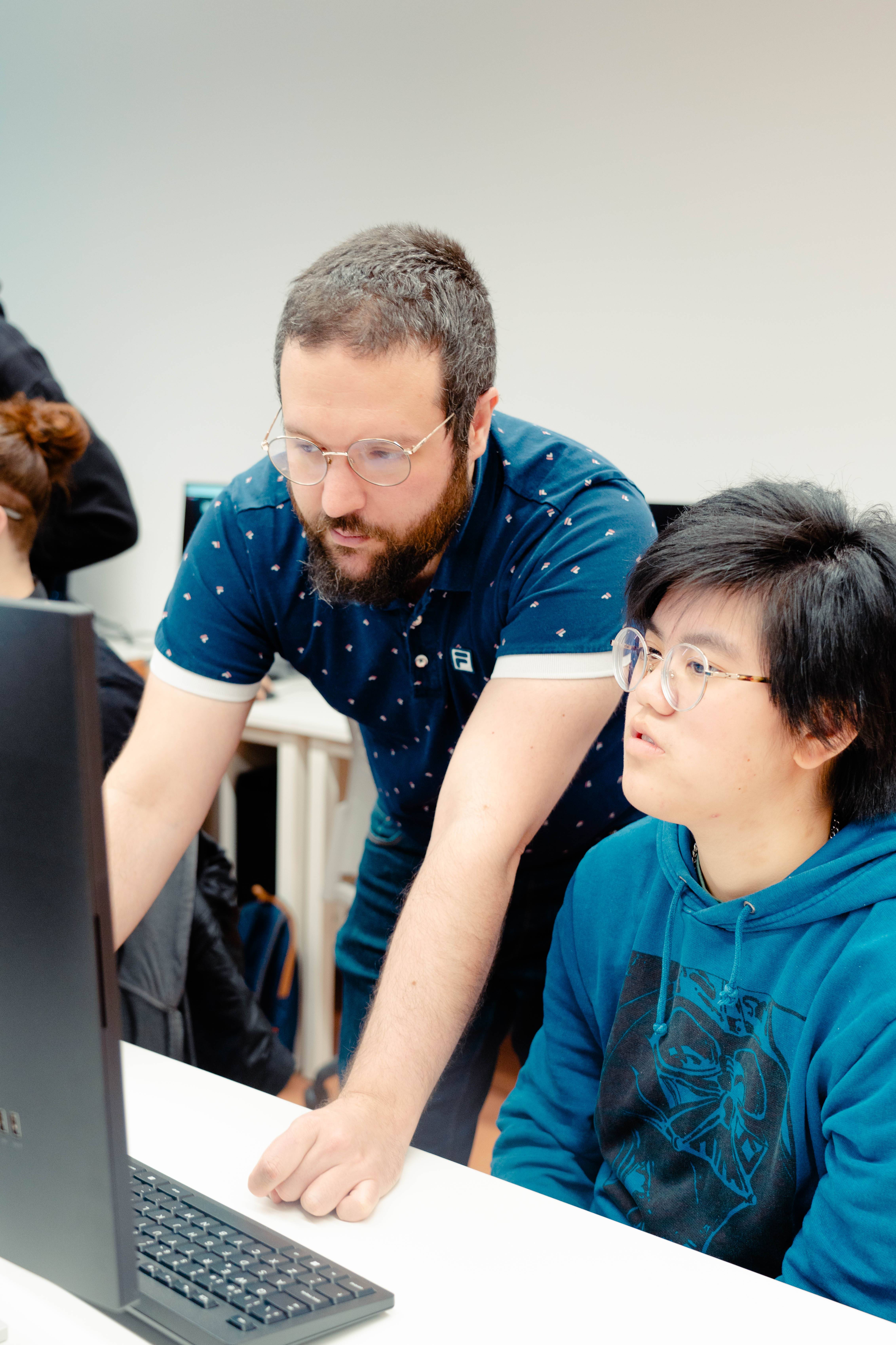 Un hombre y una mujer observan atentamente la pantalla de un ordenador en un entorno de trabajo colaborativo.