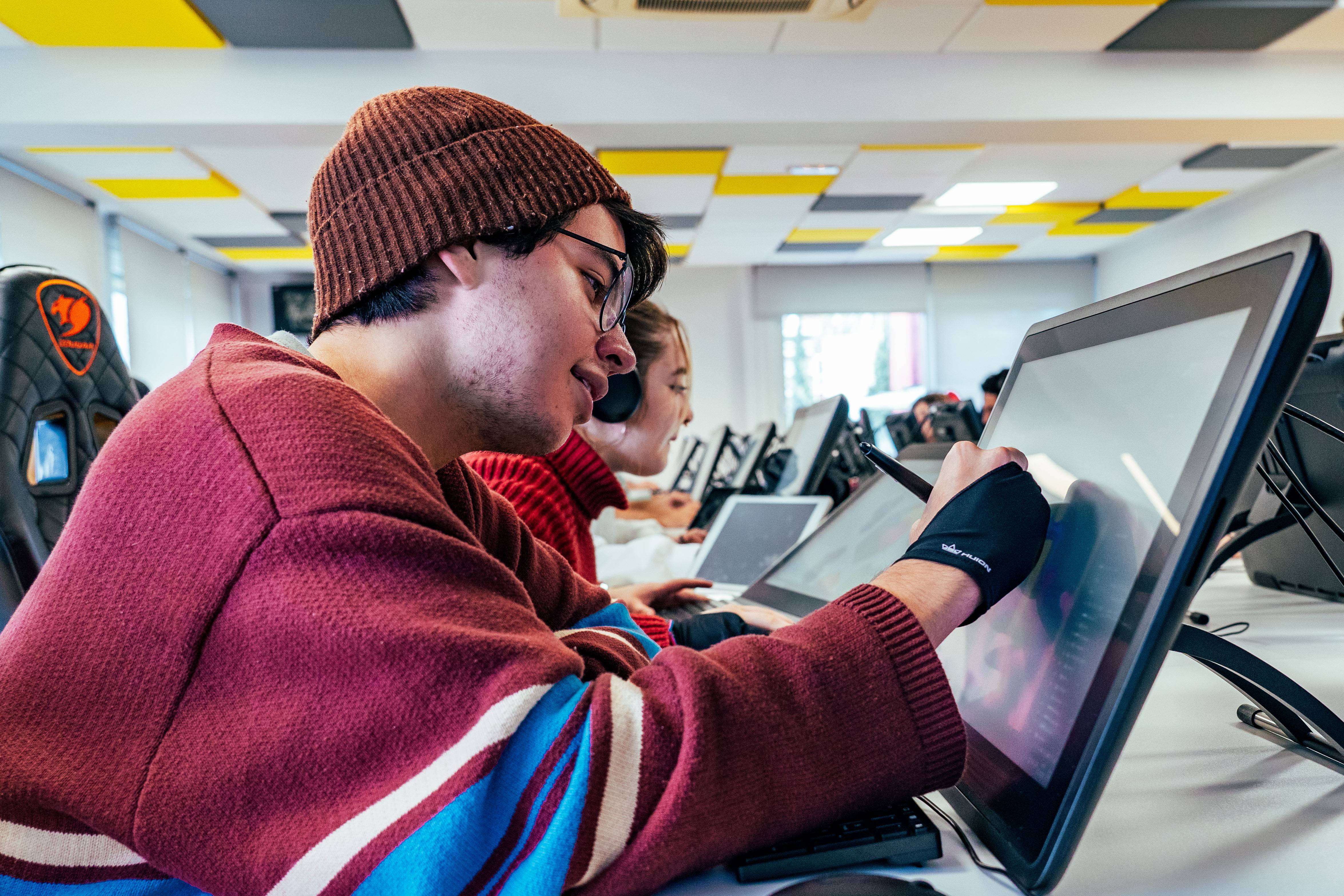 Un grupo de estudiantes trabaja en tabletas gráficas en un aula moderna.