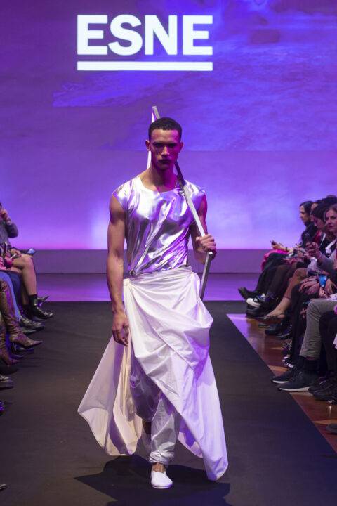 Un modelo presenta una vestimenta futurista en una pasarela de moda.