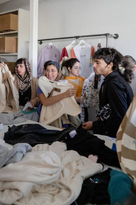 Un grupo de jóvenes se encuentra organizando prendas de vestir en una tienda o espacio de intercambio de ropa.