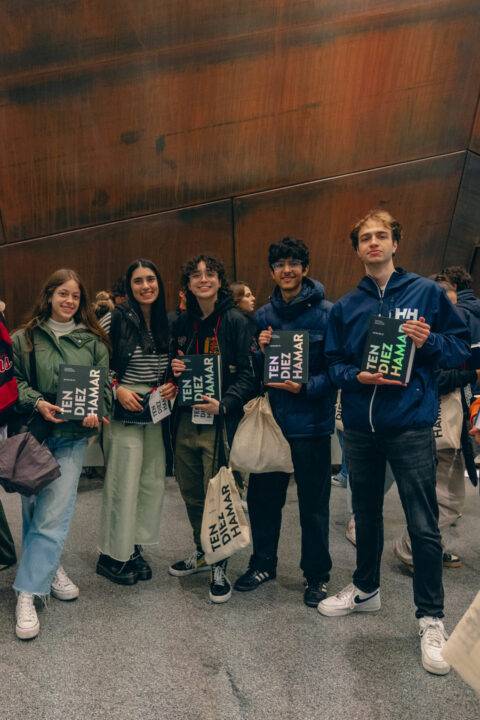 Un grupo de cinco jóvenes sostiene carteles en un evento o exposición.