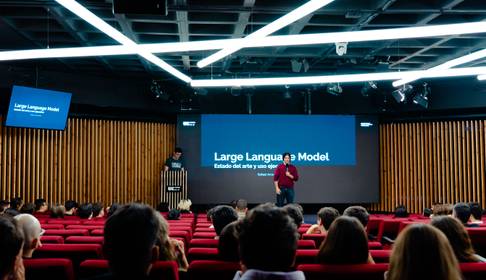 Una presentación sobre modelos de lenguaje en un auditorio con un alto número de asistentes.