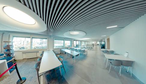 Interior de una sala moderna con mesas y sillas dispuestas en un ambiente luminoso.