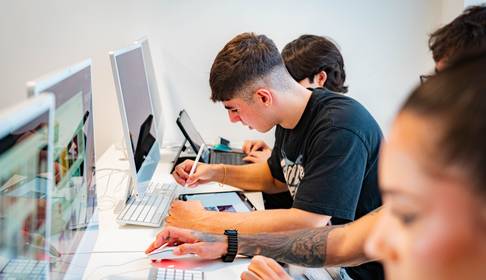 Un grupo de jóvenes trabajando en computadoras en un ambiente de estudio.