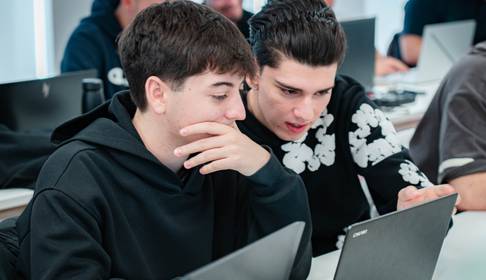 Dos jóvenes concentrados en una computadora portátil en un entorno de aprendizaje.