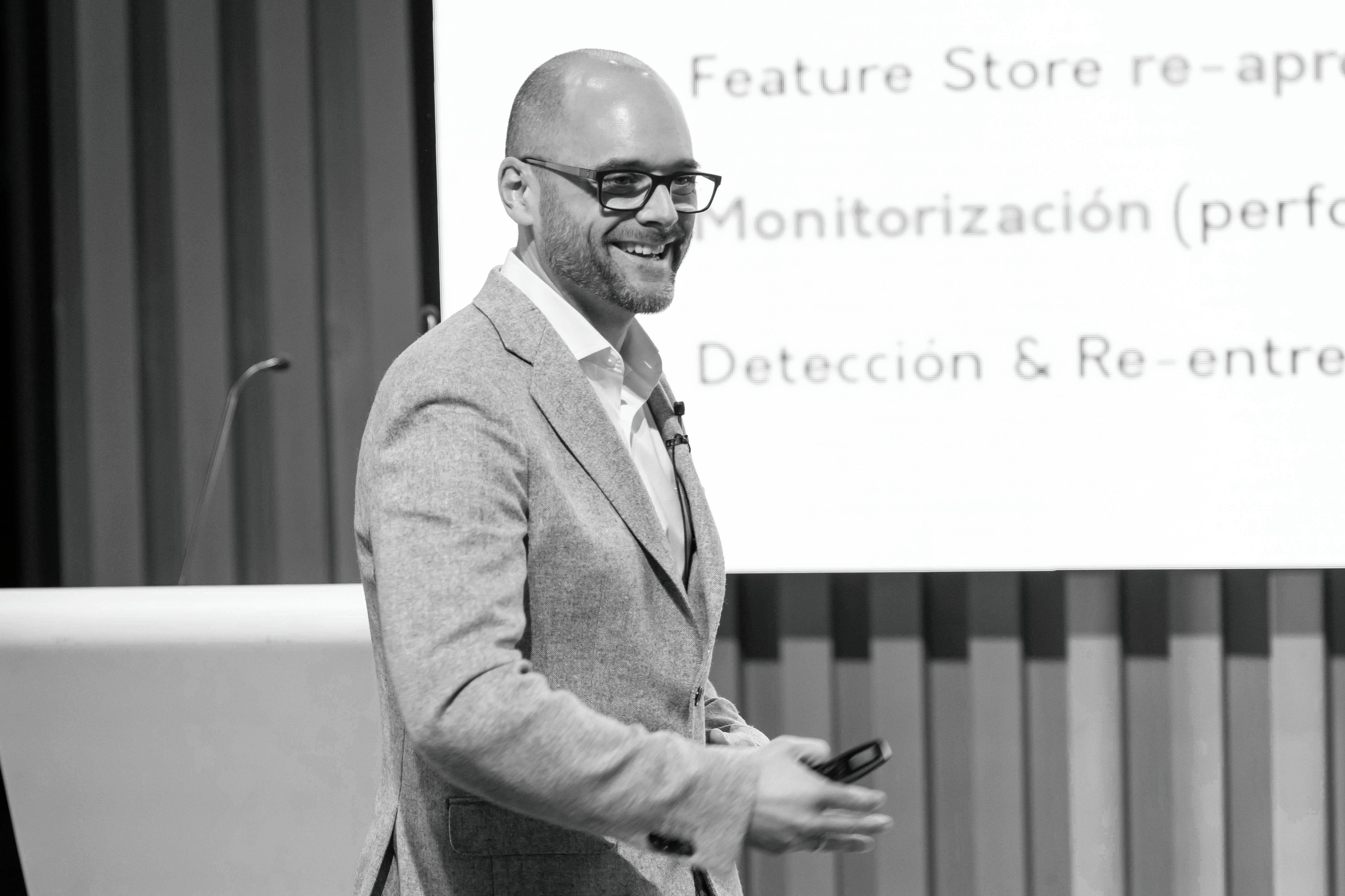 Una persona sonriente presenta sobre tecnología en un evento.