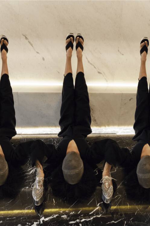 Una imagen que muestra a una persona sentada con los pies en una superficie reflectante, creando un efecto visual interesante.