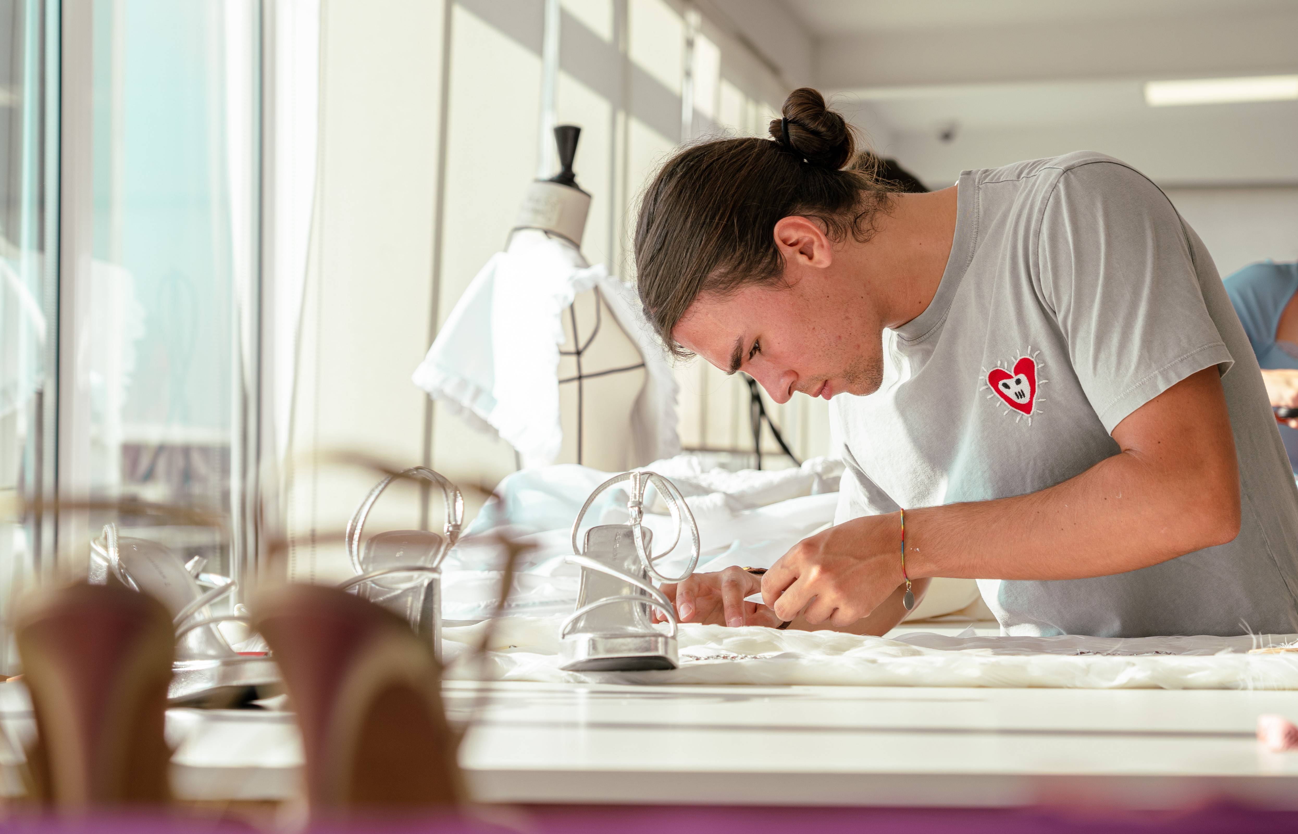 Un joven concentrado trabajan en un proyecto de costura en un taller luminoso.