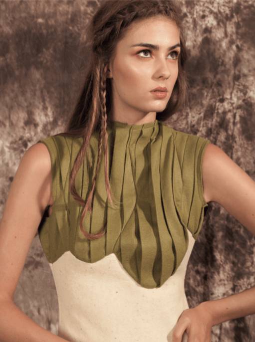 Una modelo posa con un vestido de diseño innovador en tonos verde y blanco frente a un fondo texturizado.