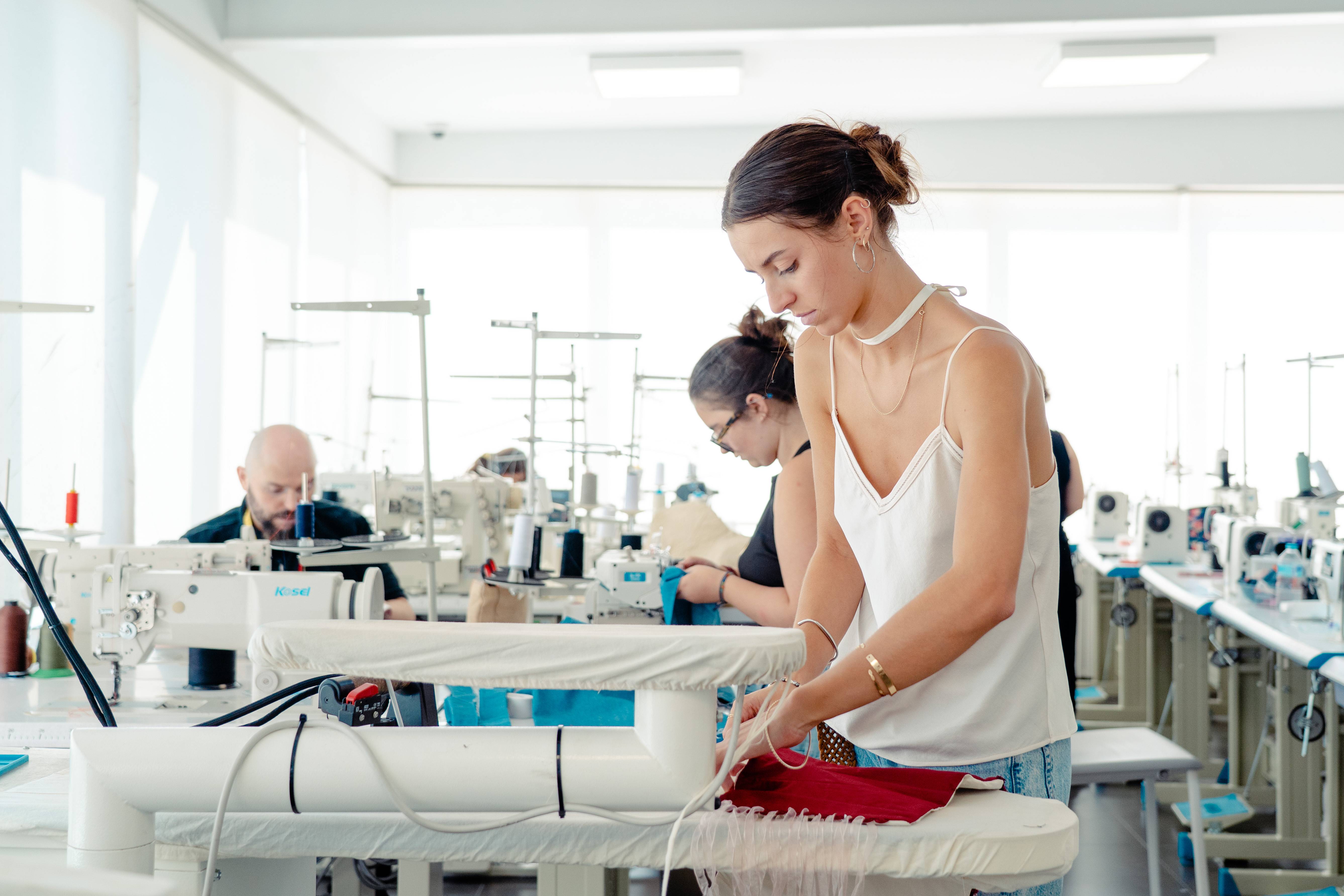 Una mujer trabaja concentrada en una máquina de coser en un taller de confección.