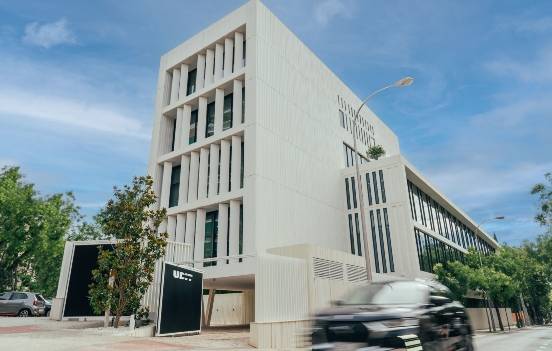 Edificio moderno con fachada blanca y elementos arquitectónicos distintivos en un entorno urbano.