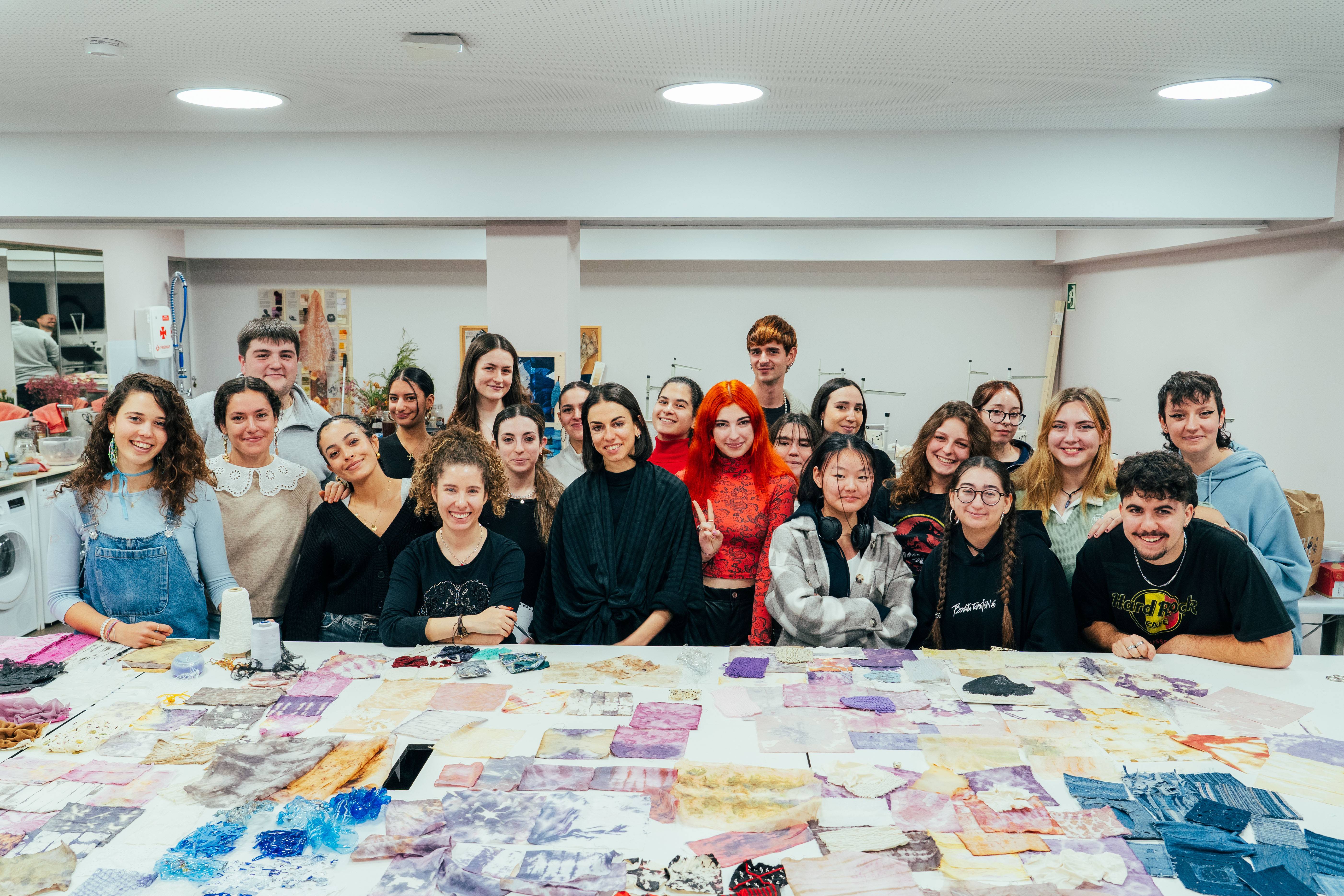 Un grupo de estudiantes sonríen y posan juntos en un taller artístico rodeados de materiales creativos.