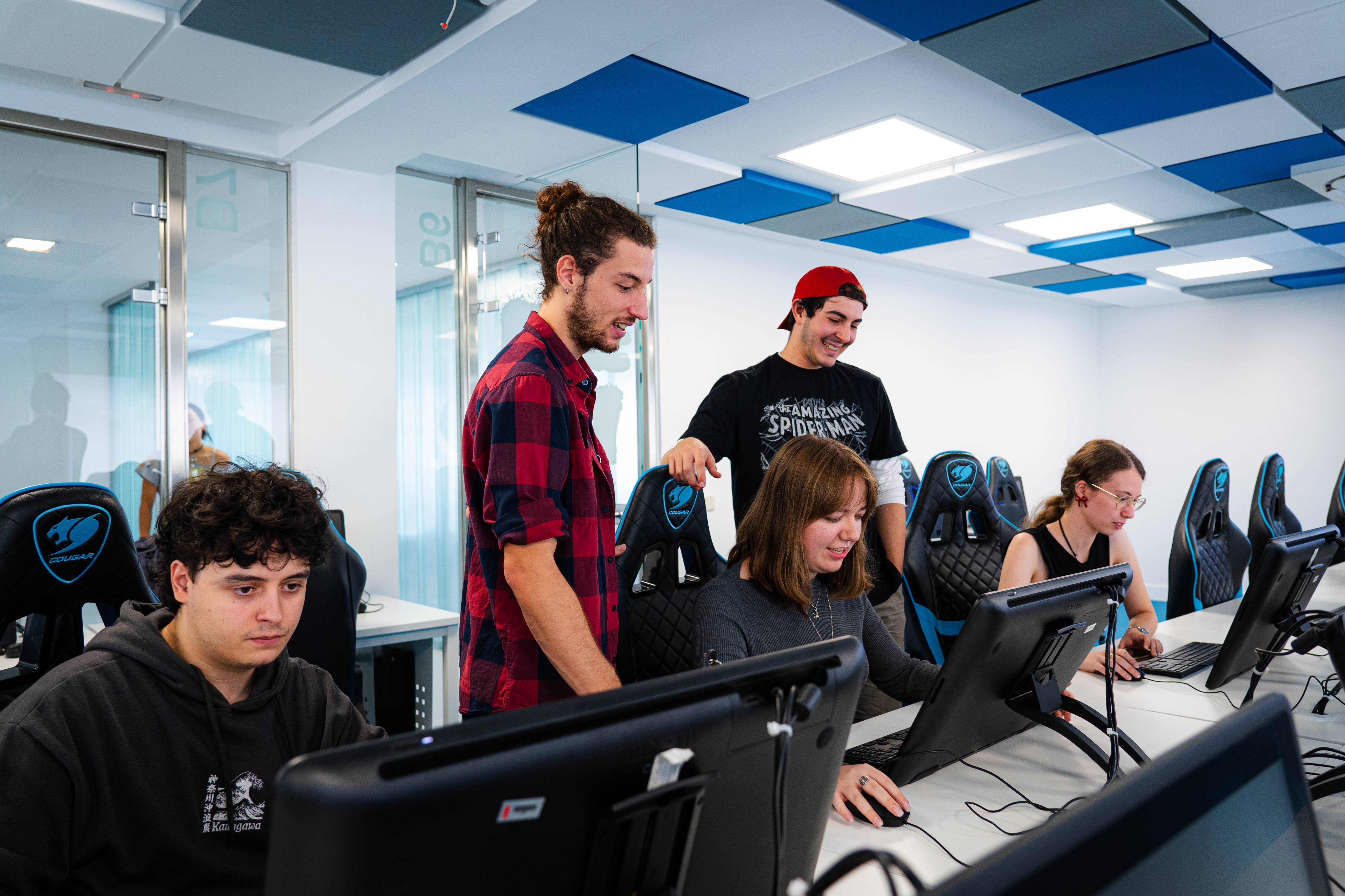 Un grupo de jóvenes trabajando en computadoras en un ambiente moderno y colaborativo.