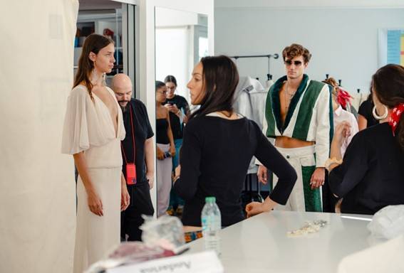 La imagen muestra un grupo de personas en un entorno de moda durante una sesión de fotos.