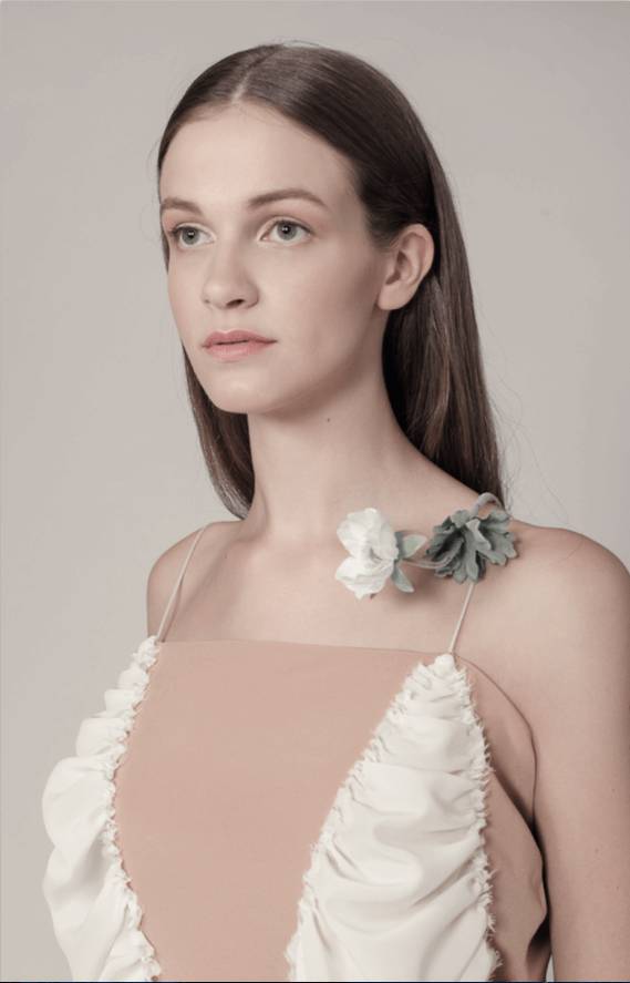 Una mujer con un vestido elegante y detalles florales en el hombro.