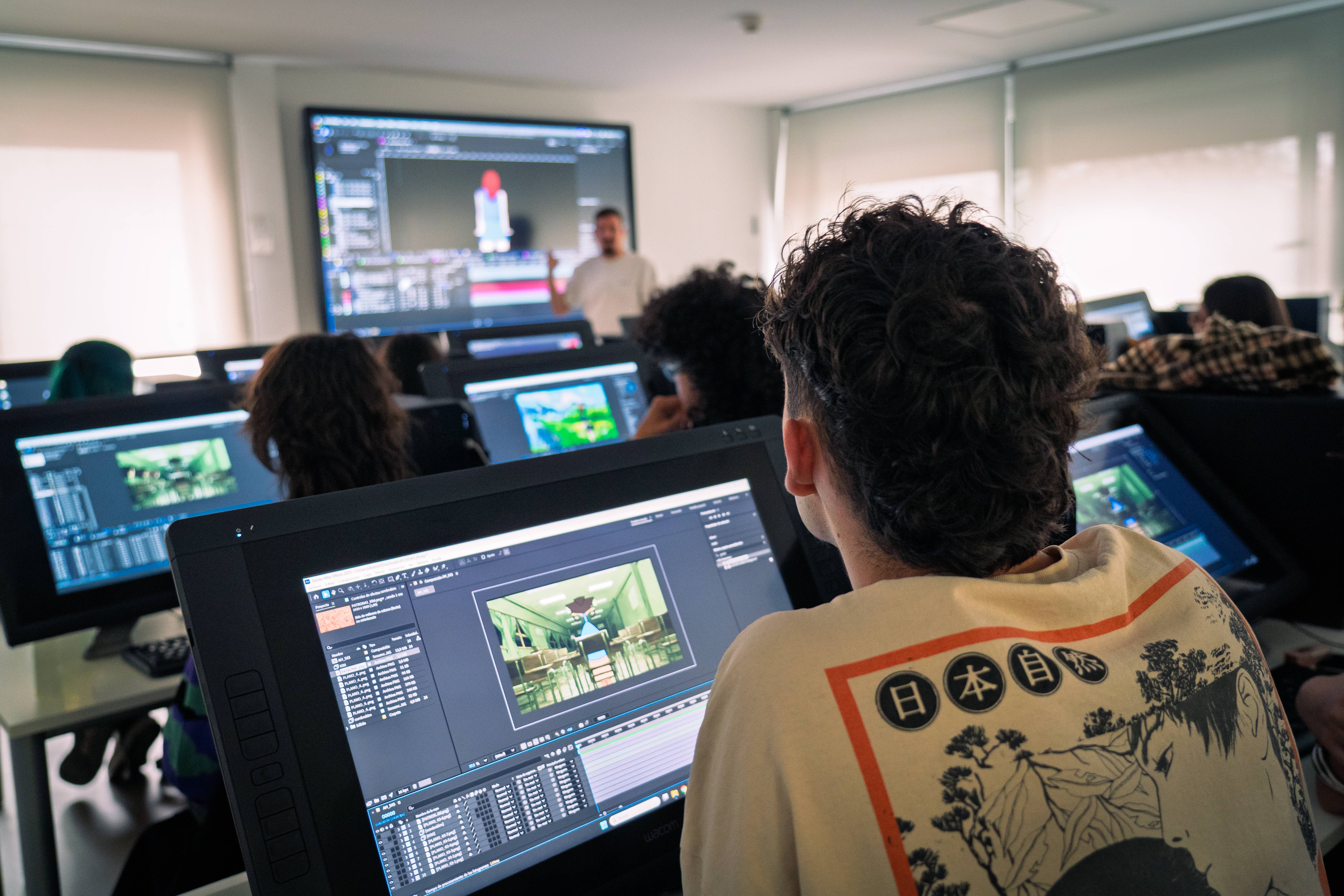 Un grupo de estudiantes asiste a una clase de arte digital frente a pantallas.