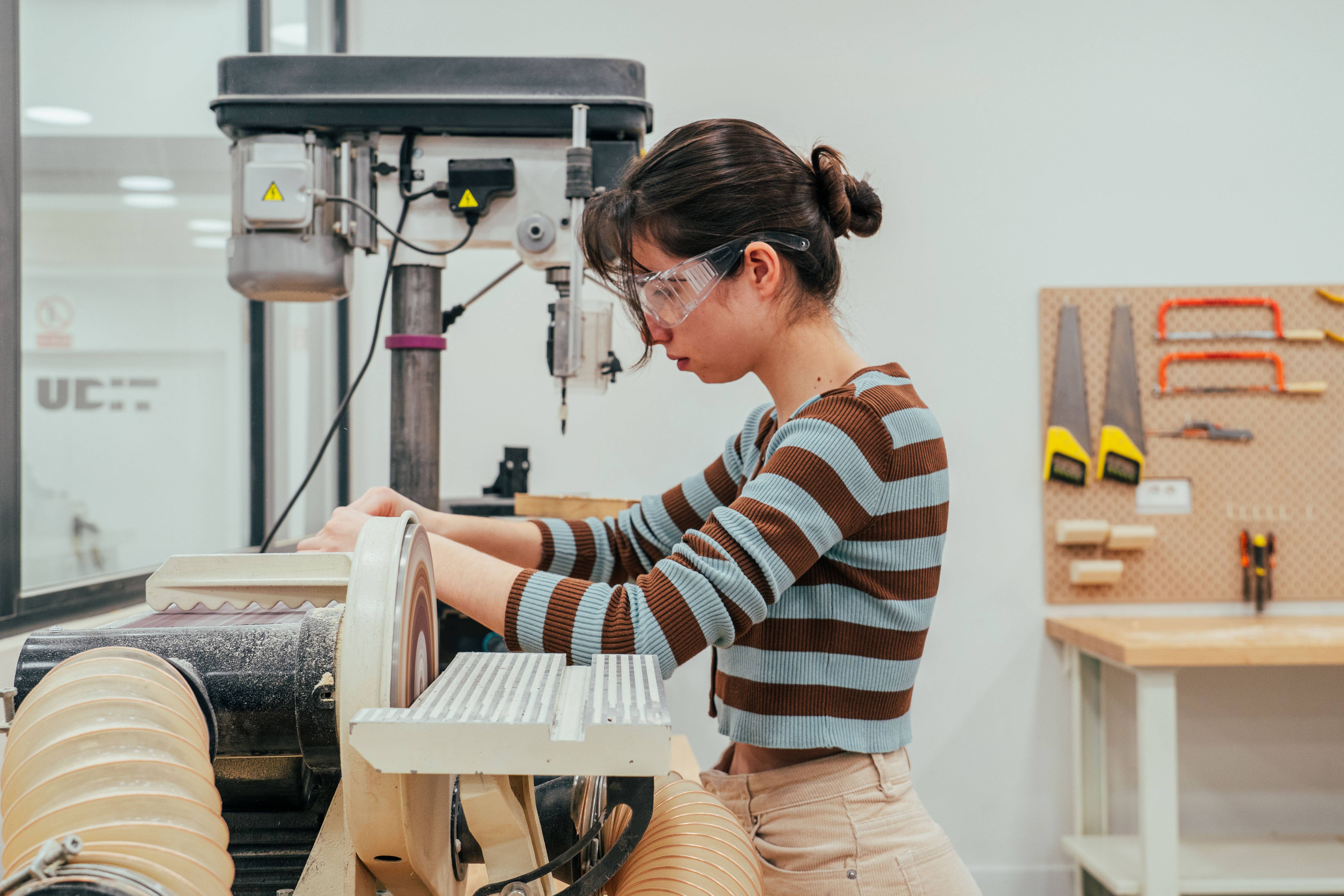 Una joven trabaja con una herramienta en un taller de carpintería.