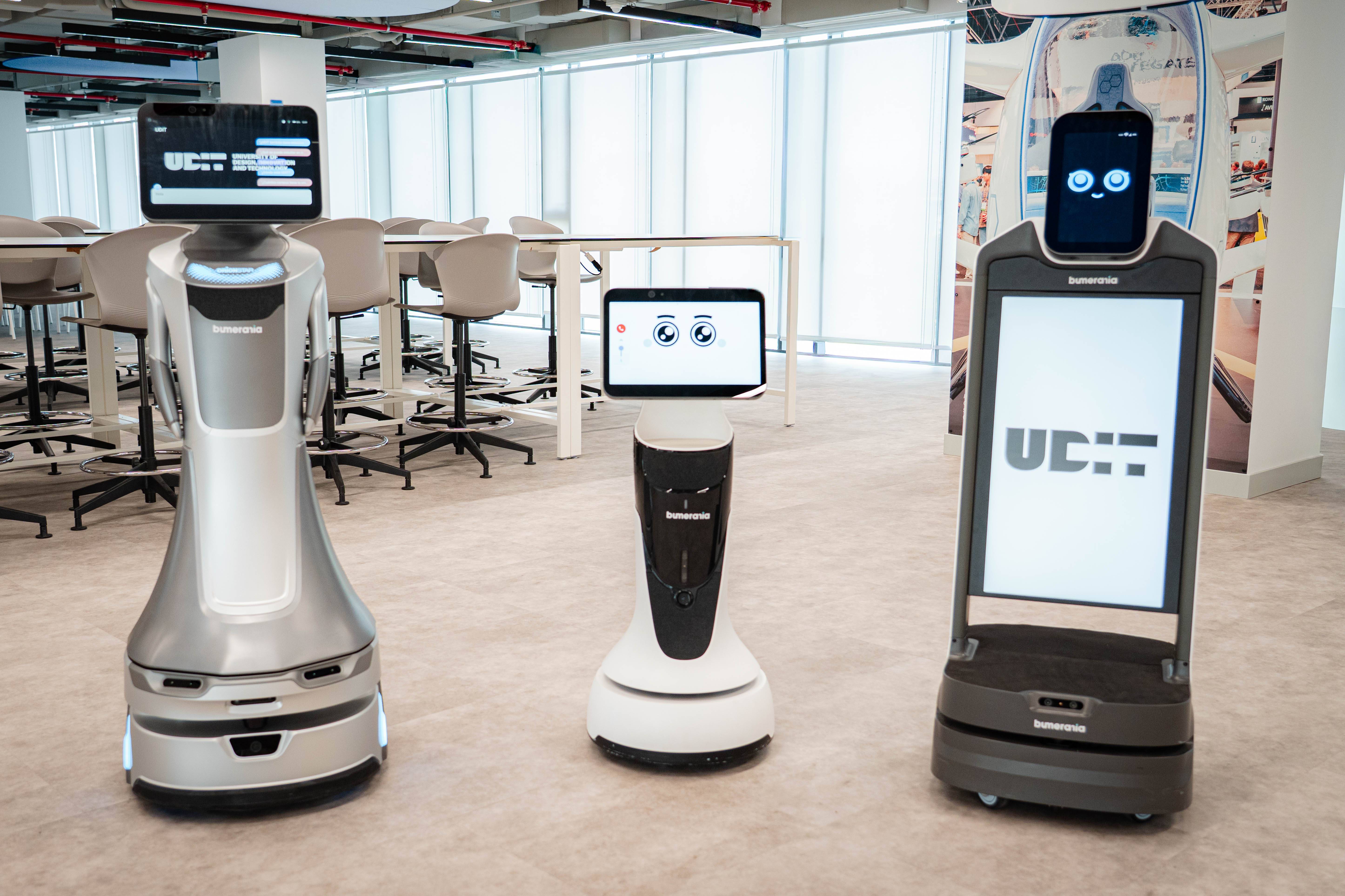 La imagen muestra tres robots de servicio en un entorno moderno de oficina.