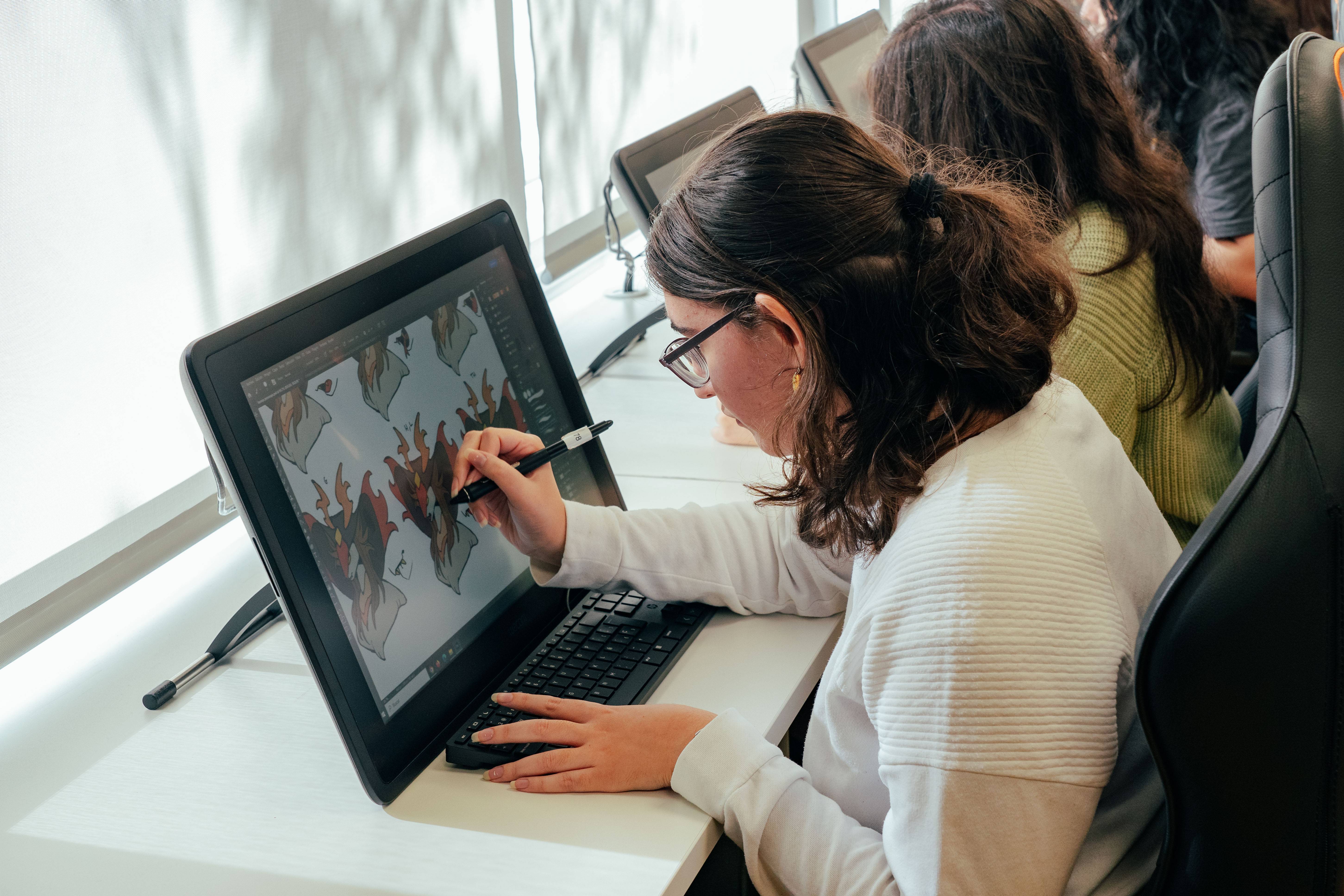 Una joven dibuja en una tableta digital en un entorno de trabajo moderno.
