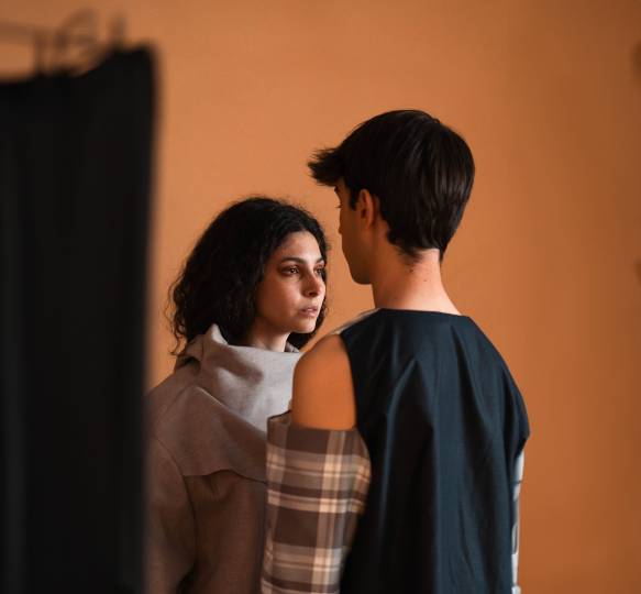 Una pareja de jóvenes se observa intensamente en un ambiente minimalista.