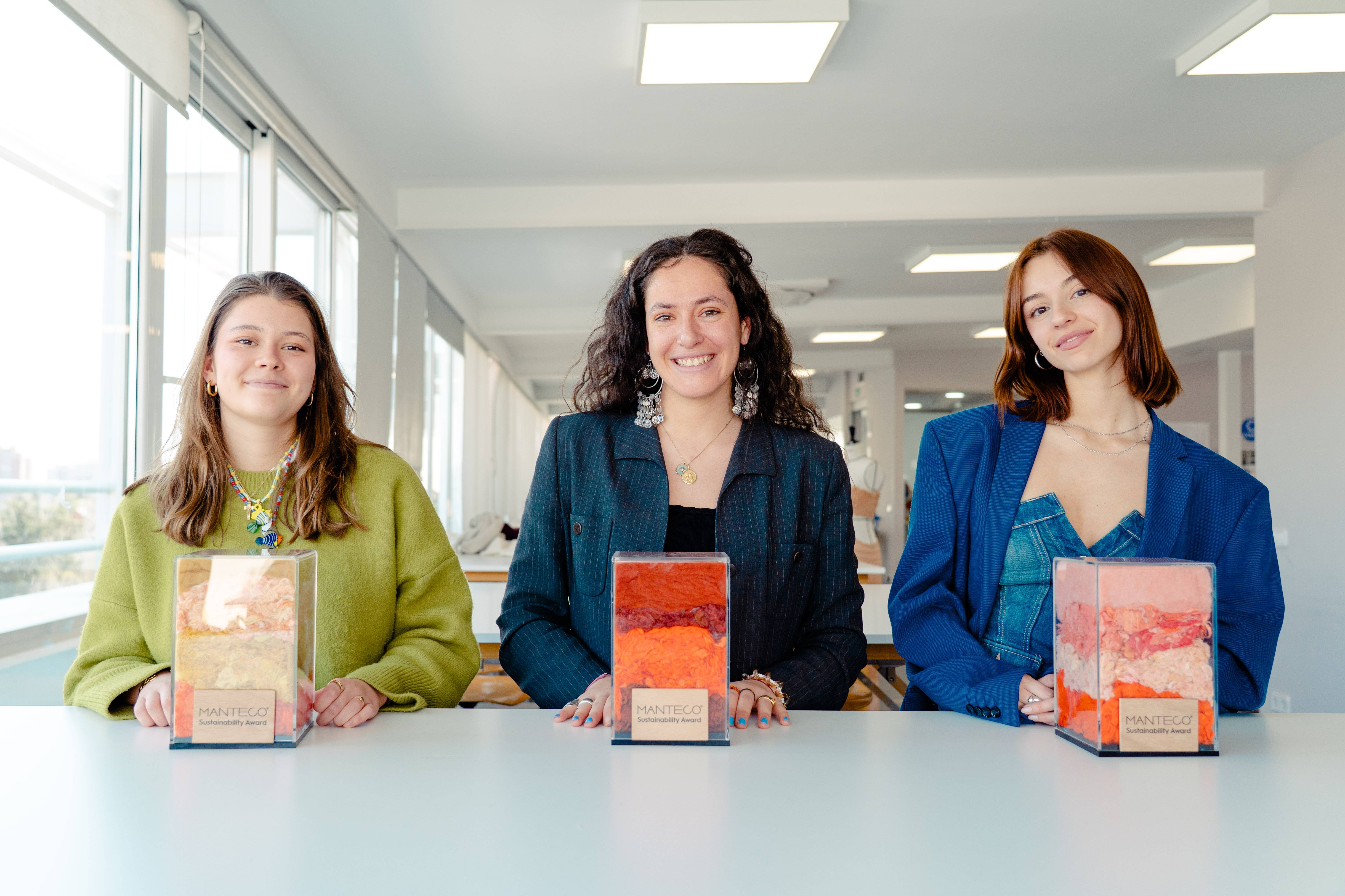 Tres mujeres posan sonrientes frente a tres cajas decorativas de colores vibrantes en un entorno luminoso.