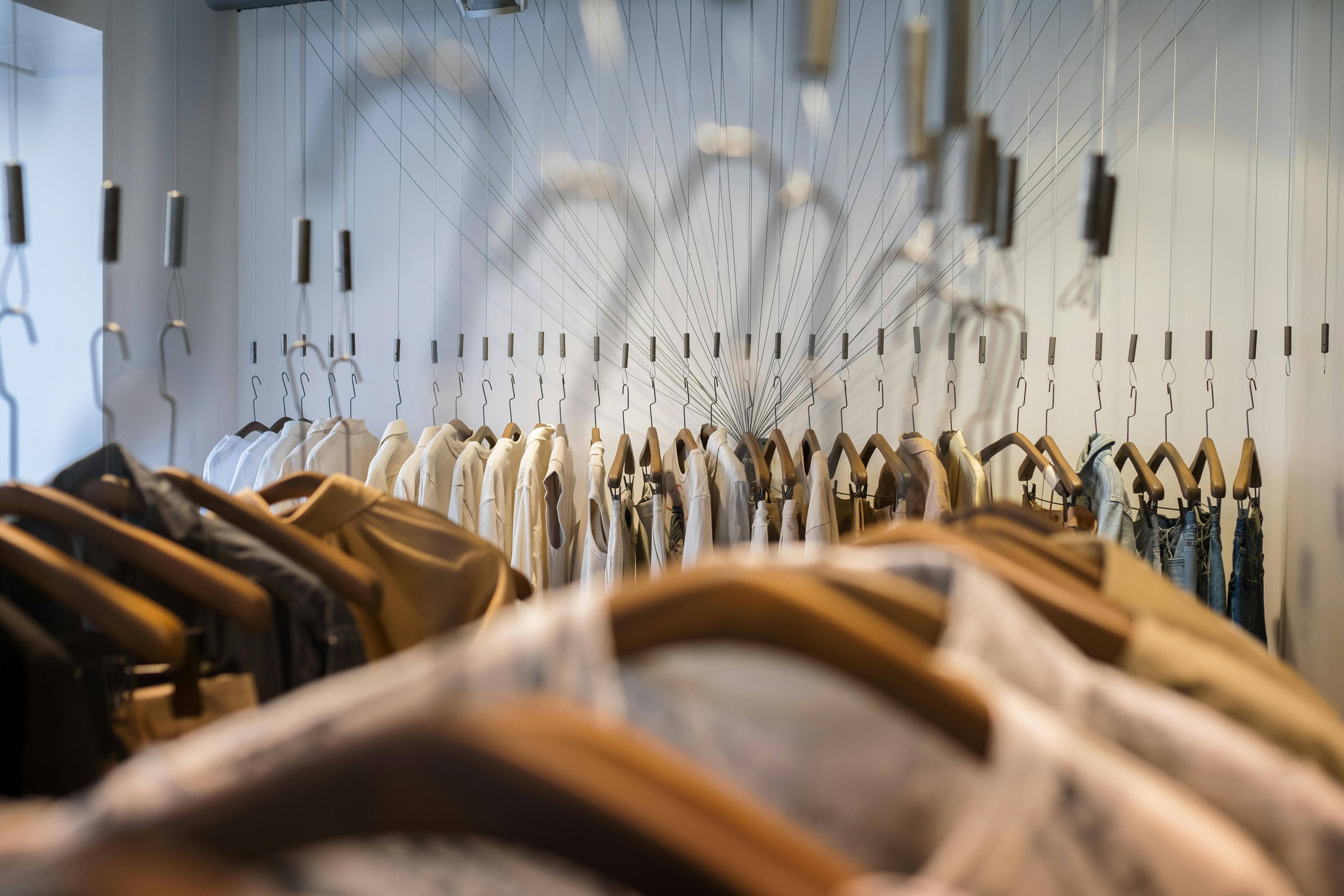 La imagen muestra un armario con prendas de ropa colgadas en perchas de madera.