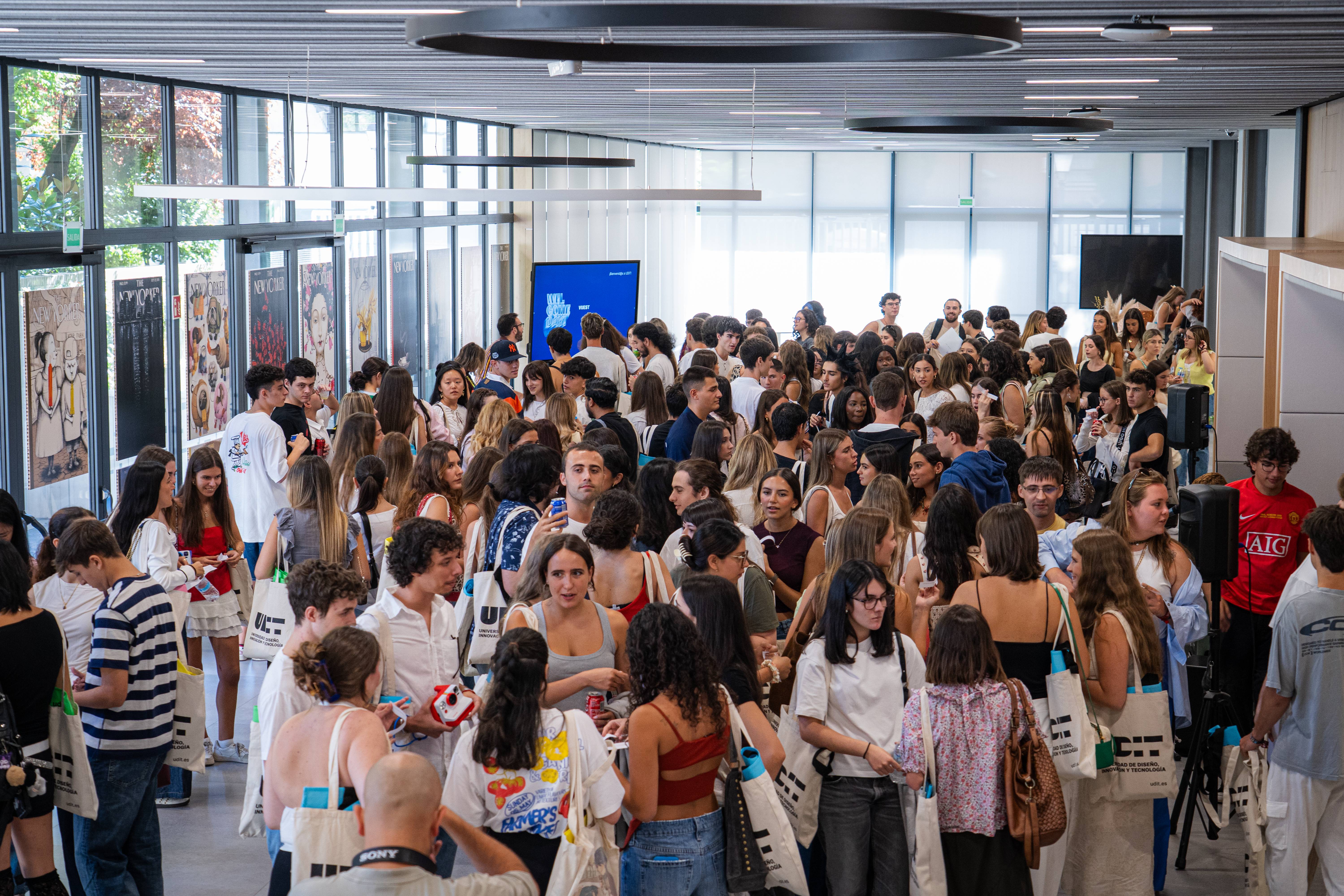 Una multitud de personas se reúne en un espacio amplio y luminoso, interactuando entre sí.