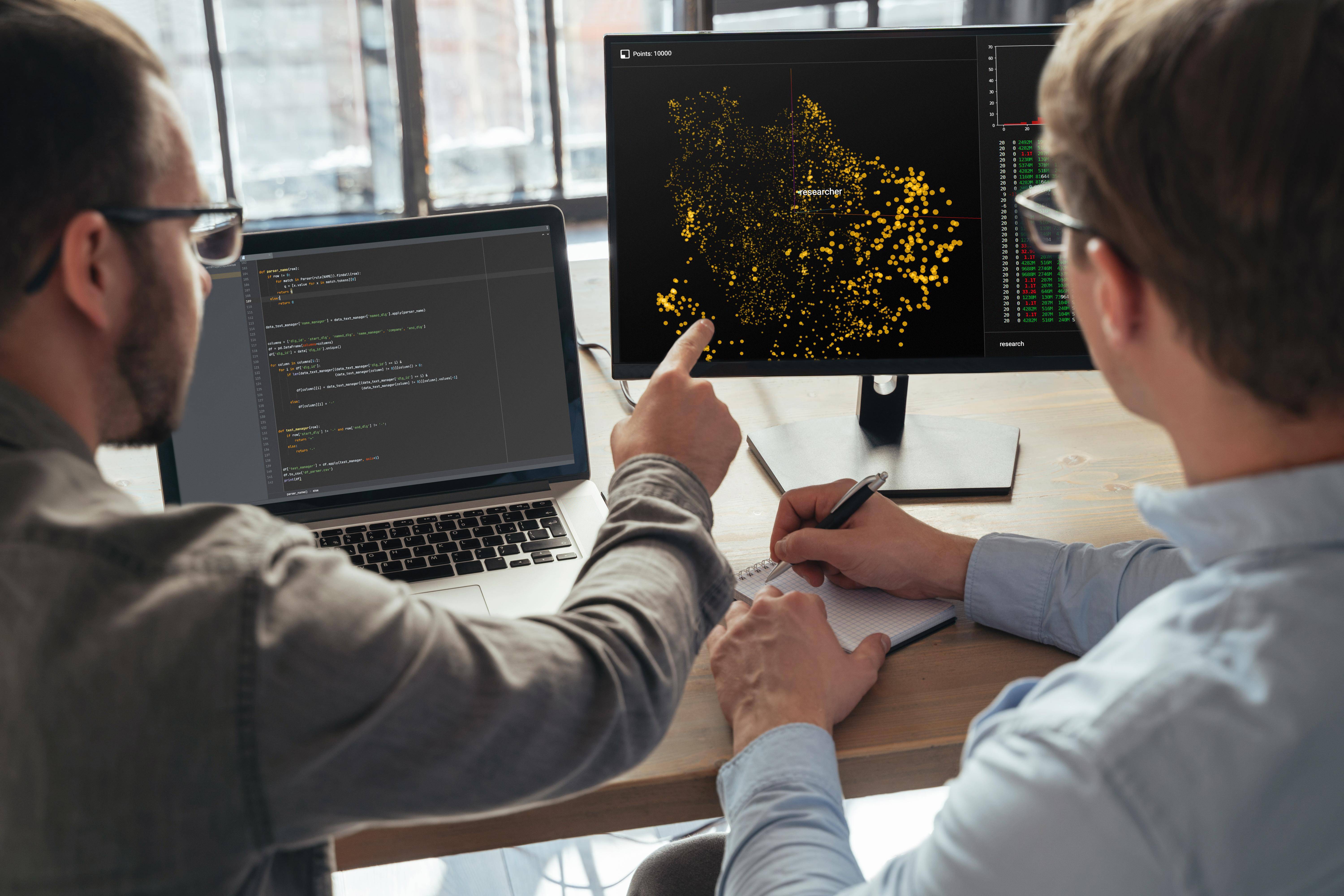 Dos personas analizando datos en una computadora y un monitor.