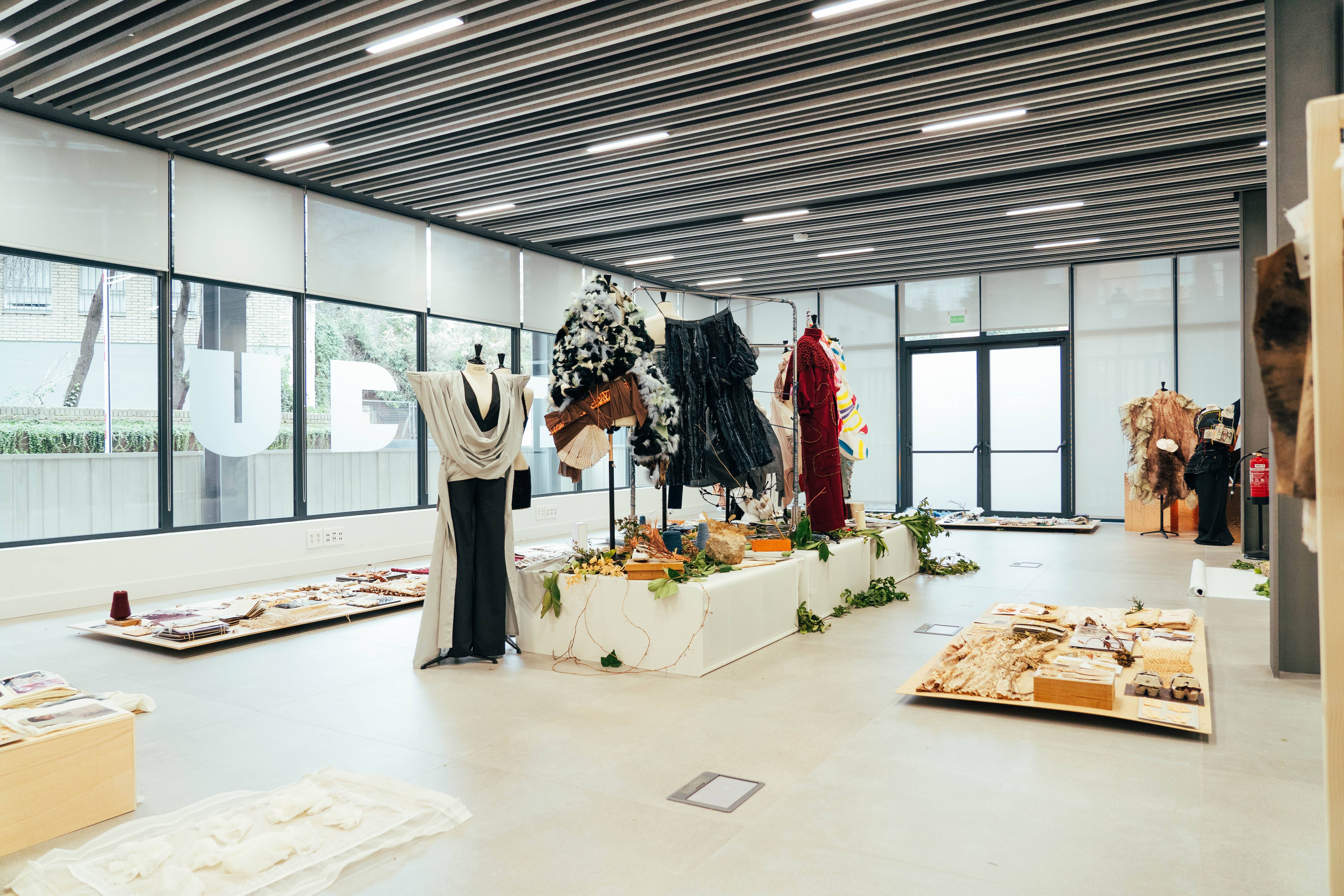 Una sala de exposición con diversas prendas de vestir y display de arte en un ambiente contemporáneo.
