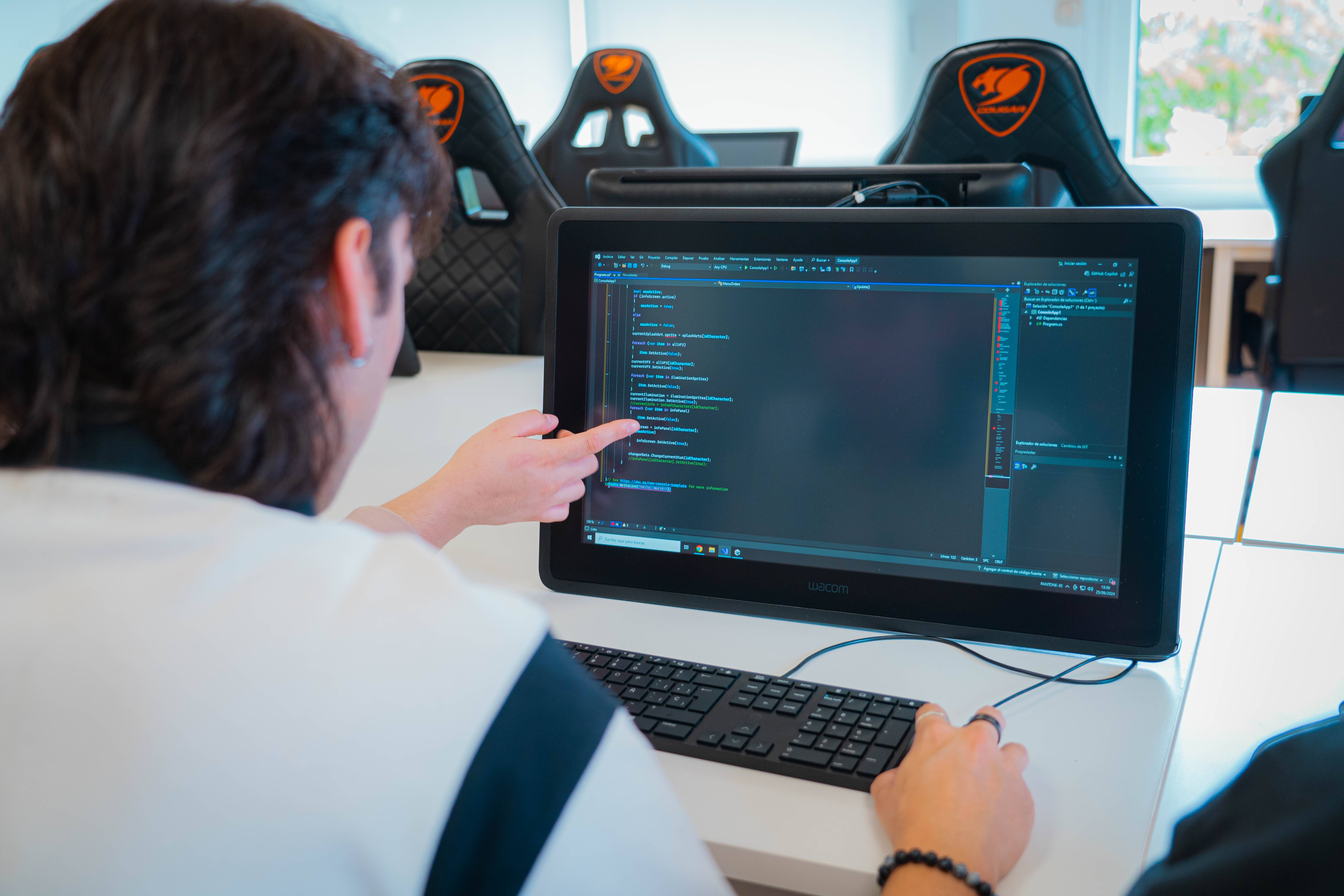 Un estudiante está programando en un ordenador en un aula moderna.