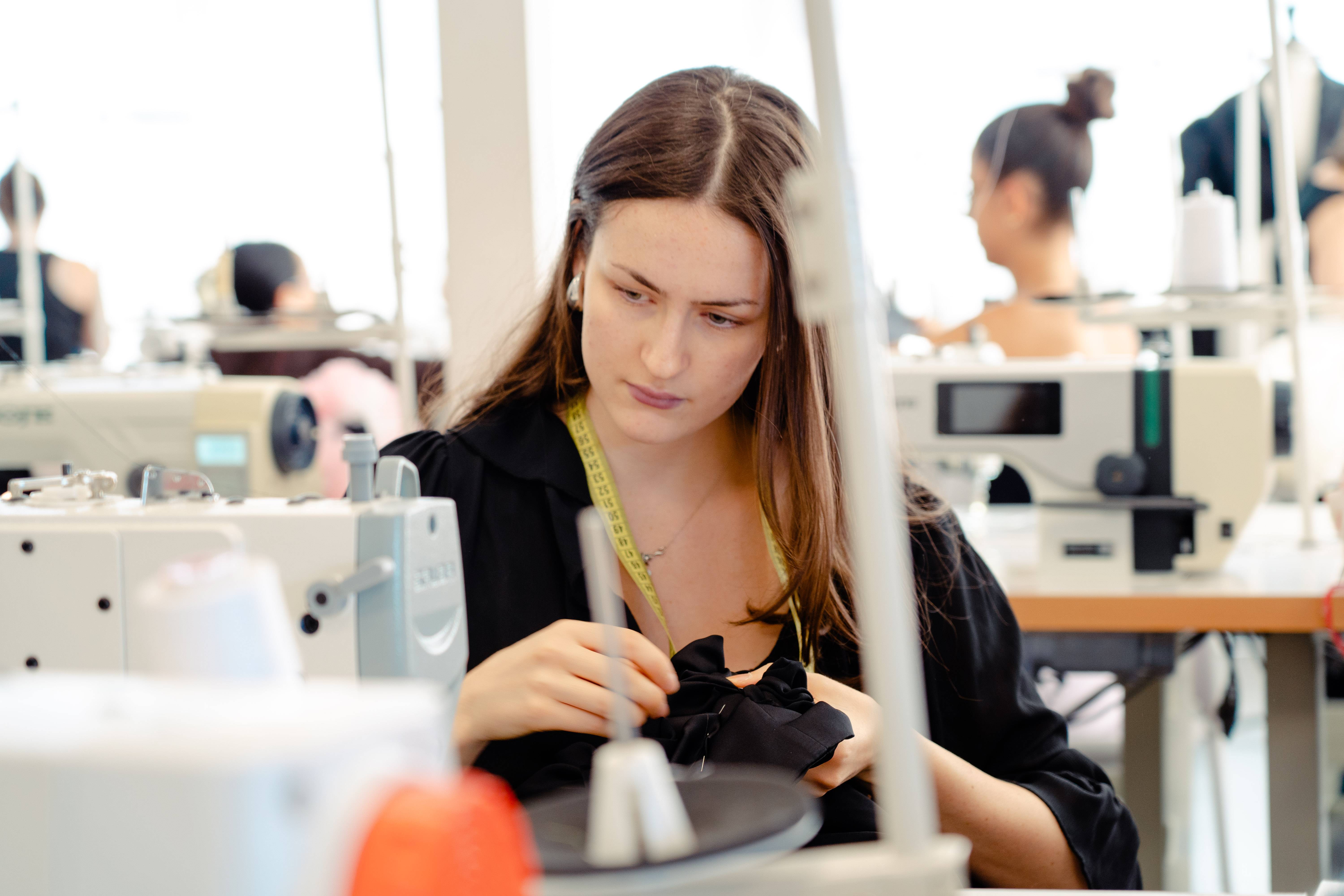 Una mujer está trabajando en una máquina de coser en un taller de confección.