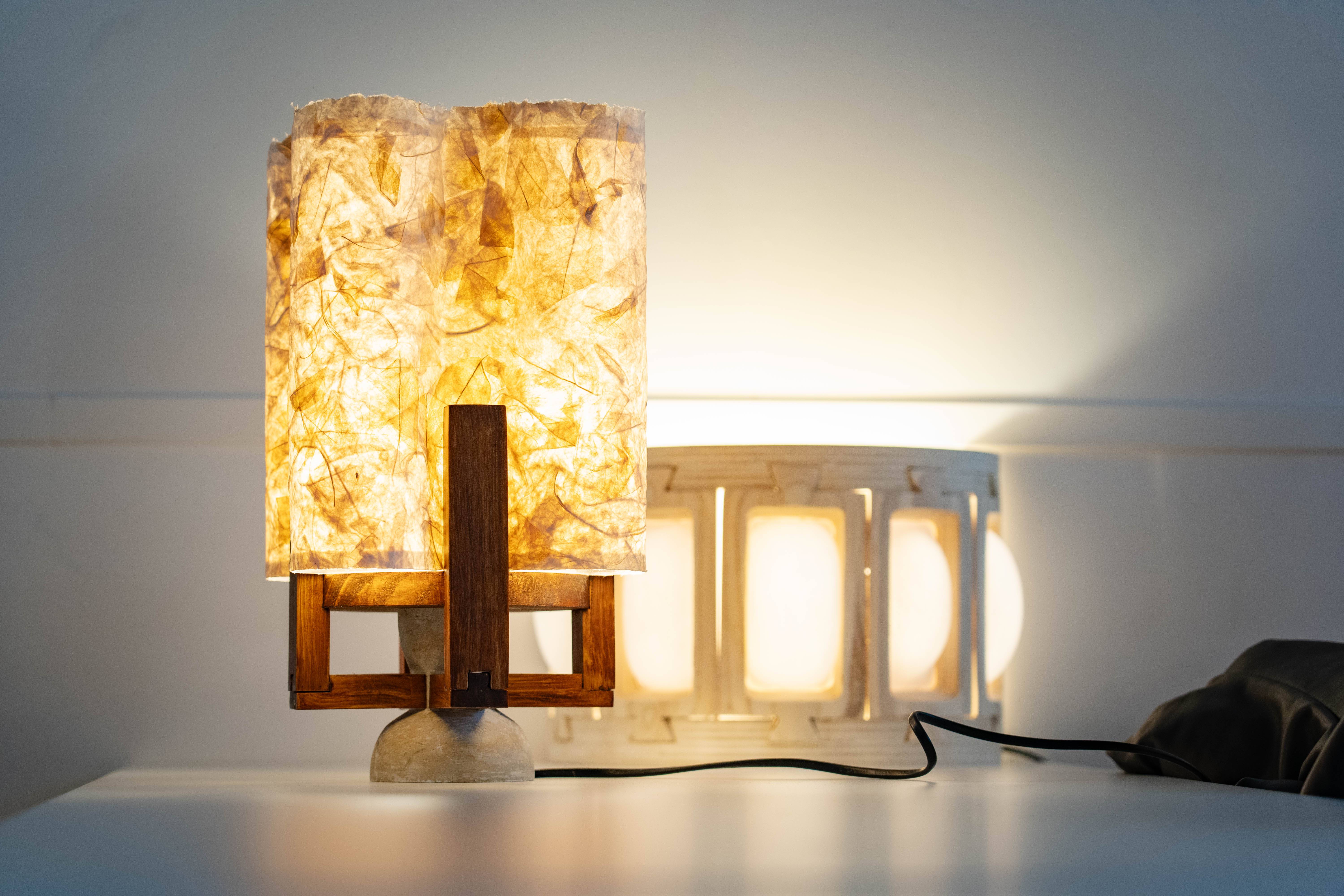 Una lámpara de mesa con pantalla iluminada de color ámbar y base de madera y metal.