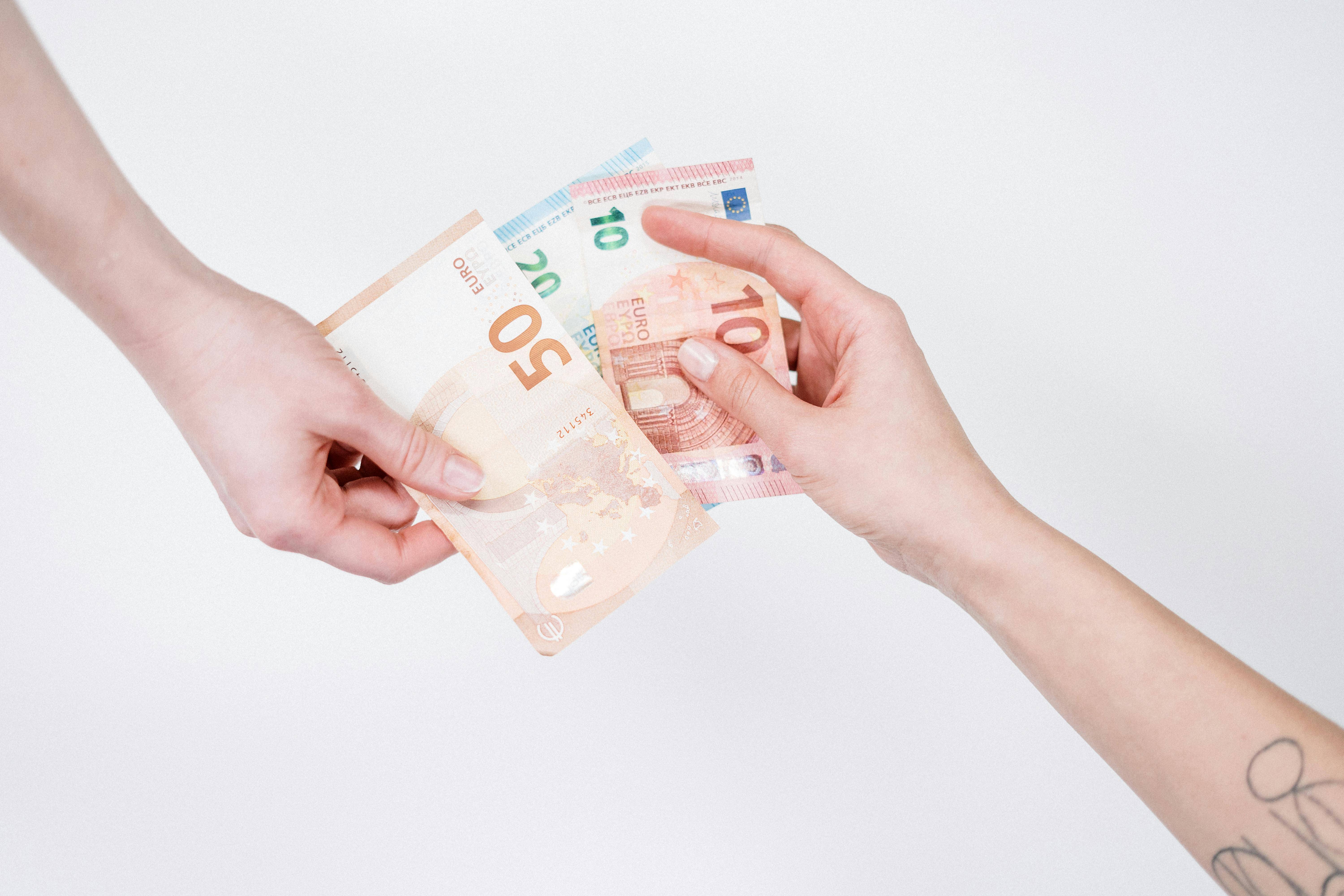 Dos manos están intercambiando billetes de euro en una transacción.