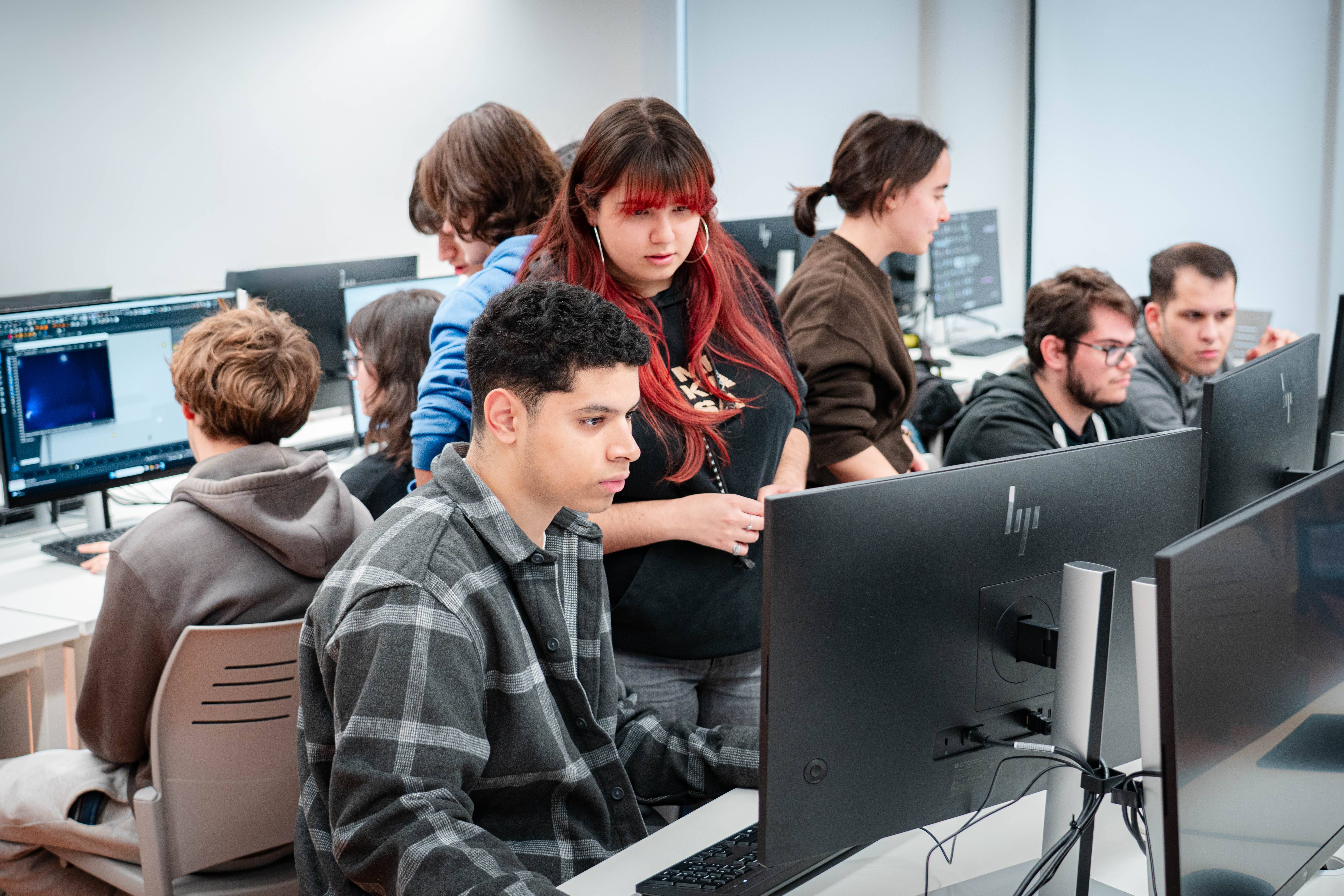 Un grupo de estudiantes trabaja en computadoras en un aula moderna.