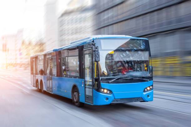 Un autobús azul en movimiento por una calle urbana.