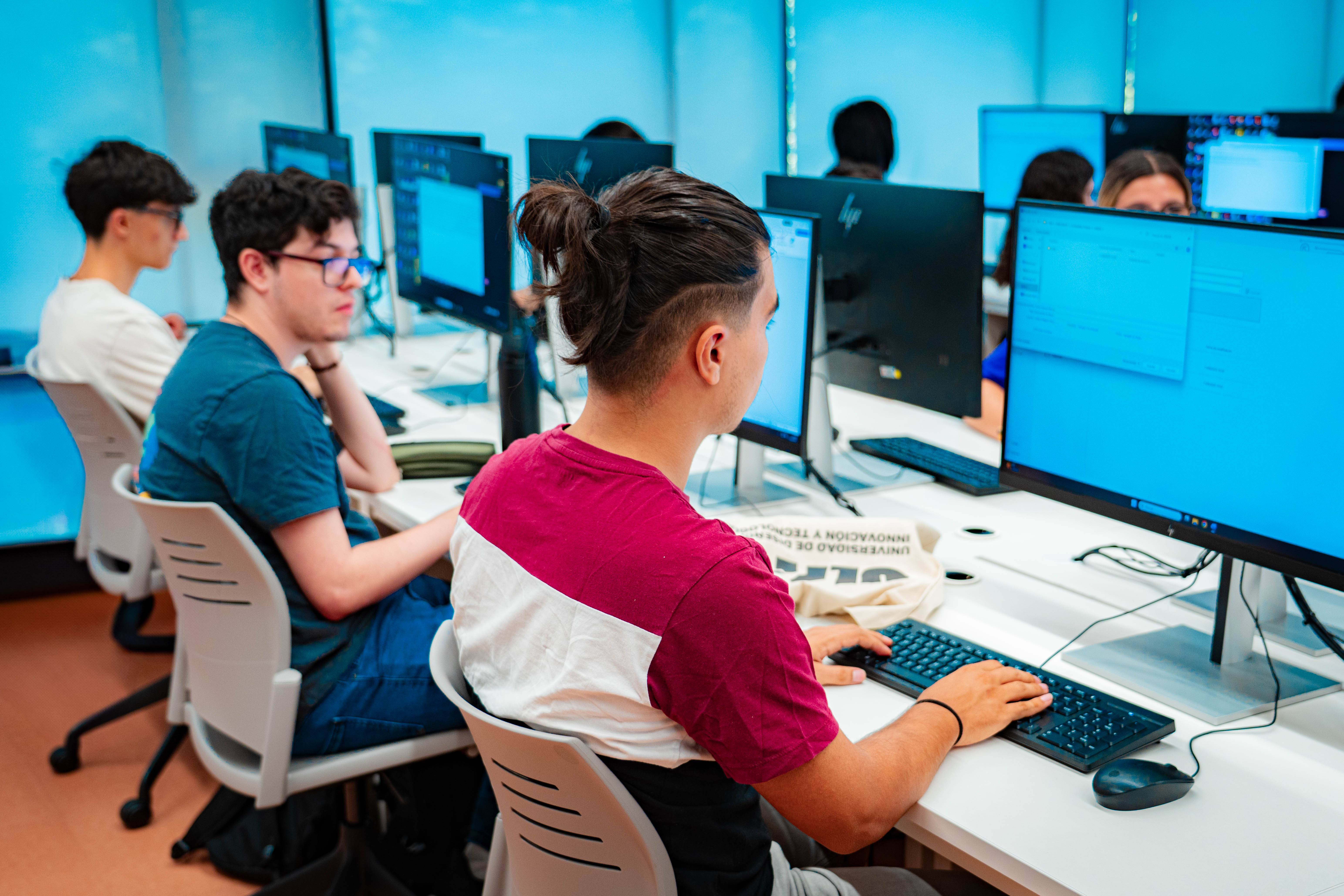 Un grupo de estudiantes trabajando en computadoras en un aula moderna.