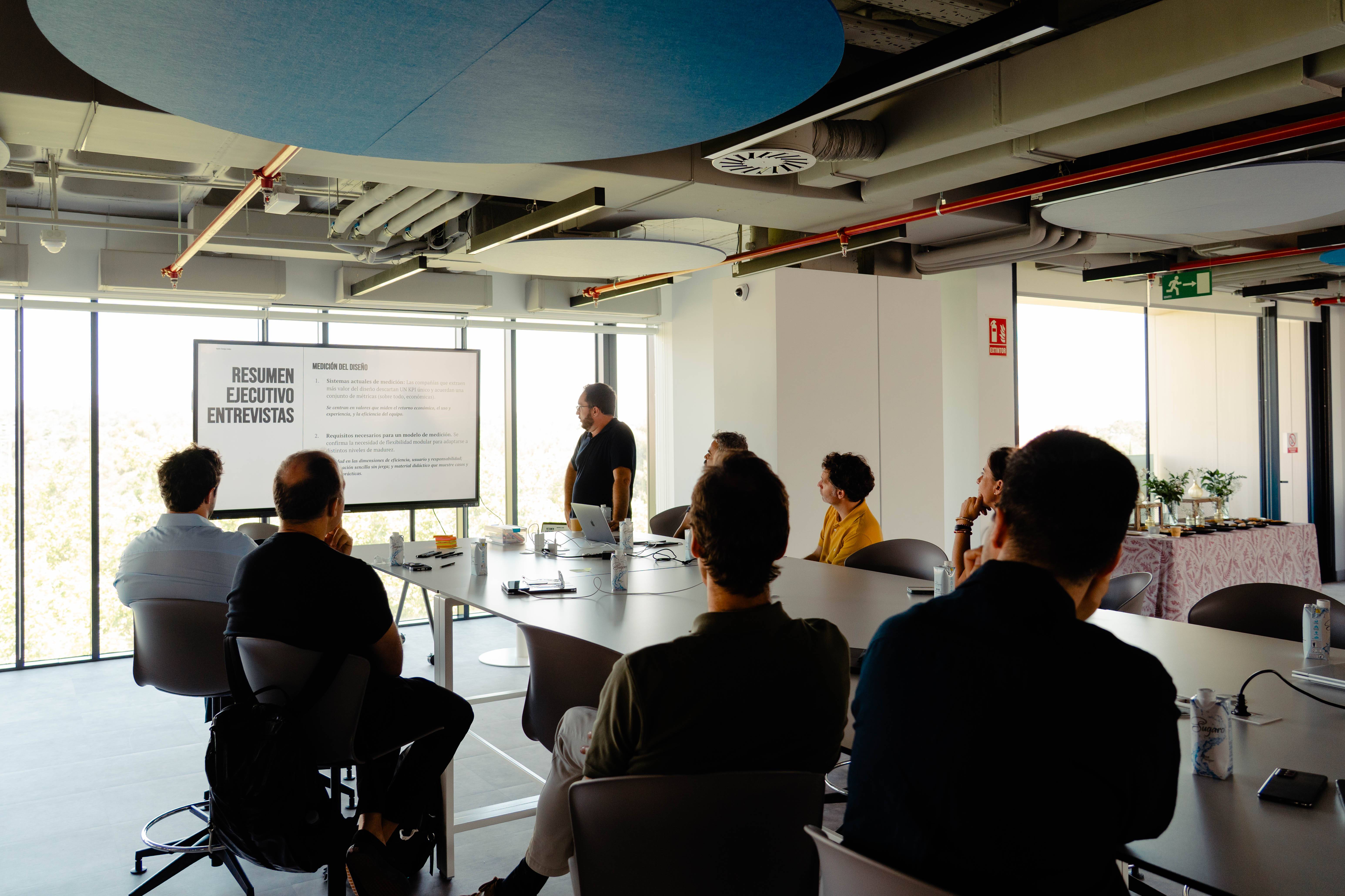Una reunión de trabajo en la que se presenta un resumen ejecutivo frente a un grupo de personas.