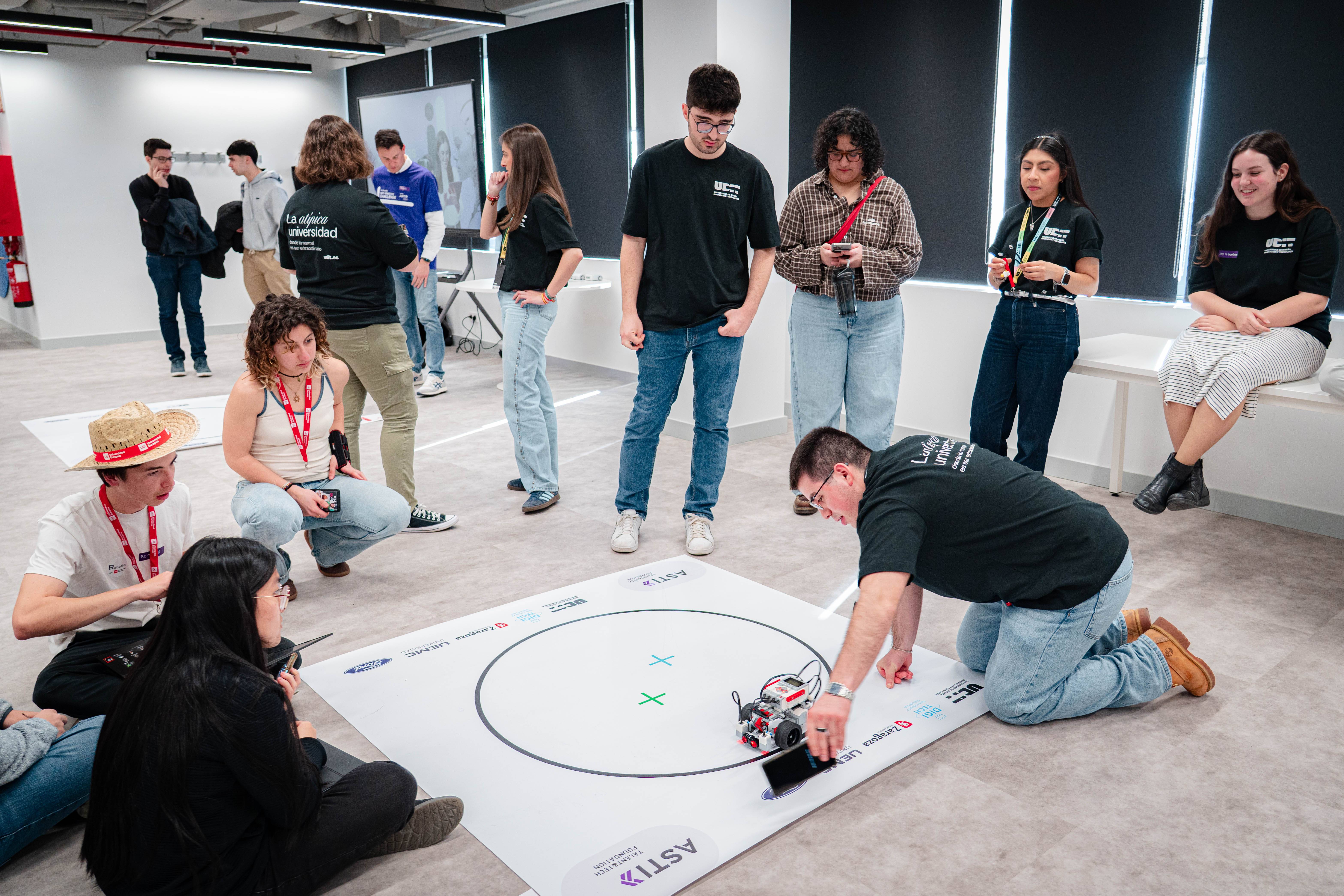 Un grupo de jóvenes participa en una actividad con robots en un espacio de trabajo moderno.