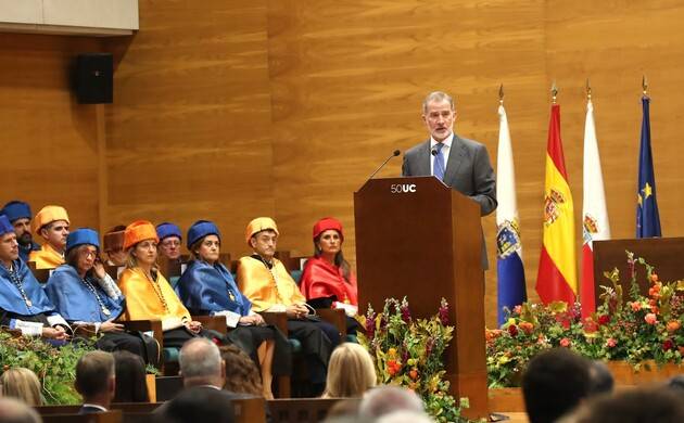 Un orador se dirige a un público durante una ceremonia académica con varios asistentes vestidos con togas de colores.